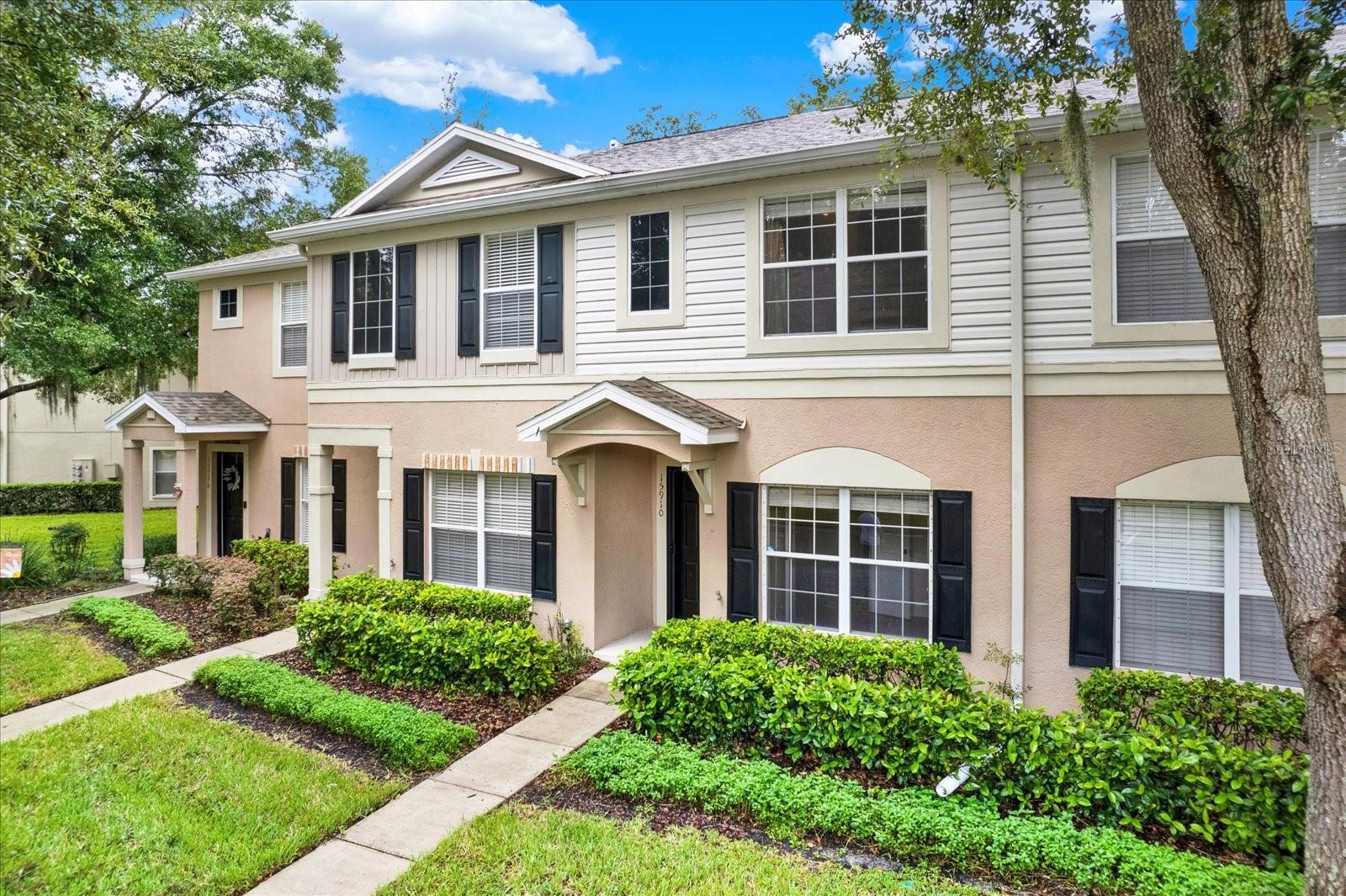 The front of the townhouse is a blend of modern and classic architectural design. The facade is clean and symmetrical, featuring large, energy-efficient windows that contrasts beautifully with the light-colored stucco exterior. A small, well-kept front garden lines the entryway, adding a touch of greenery. The front door is accented with a screen door to allow for those breathy evenings. A narrow porch leads up to the entrance, giving the home a welcoming and refined feel.