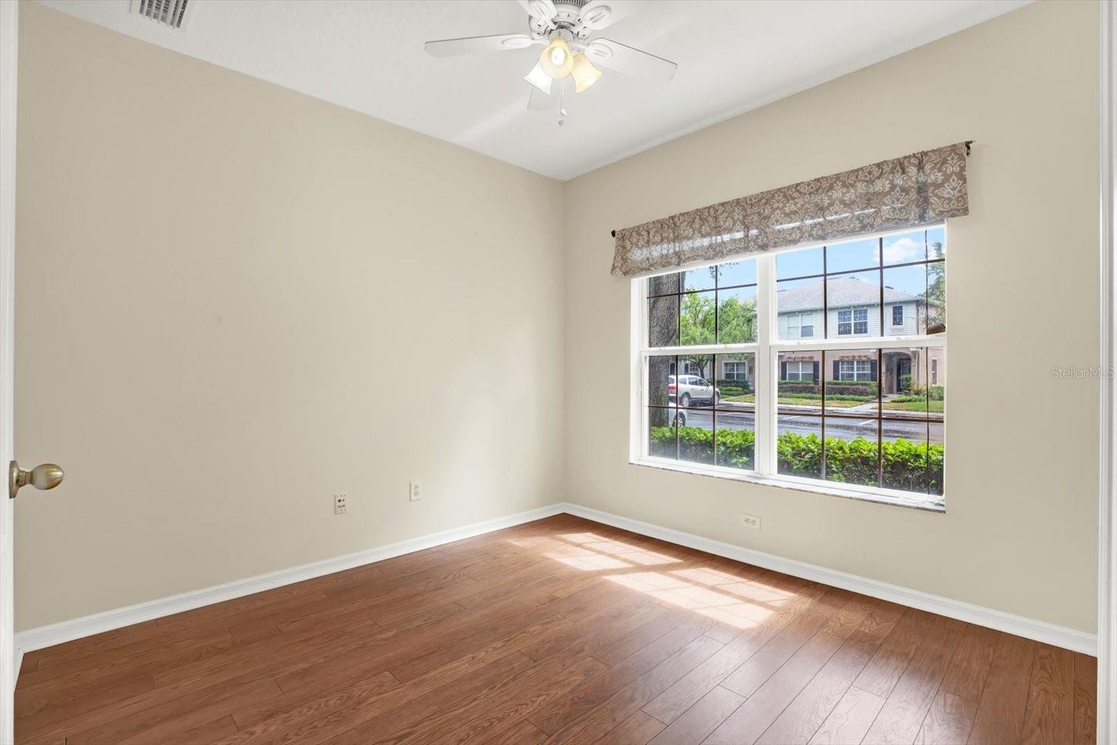 This inviting den, located at the front of the townhouse, boasts a large window that floods the space with natural light and offers a picturesque view of the neighborhood. The room features elegant wood flooring, creating a warm and welcoming atmosphere, perfect for a additional bedroom, home office, reading nook, or cozy sitting area.