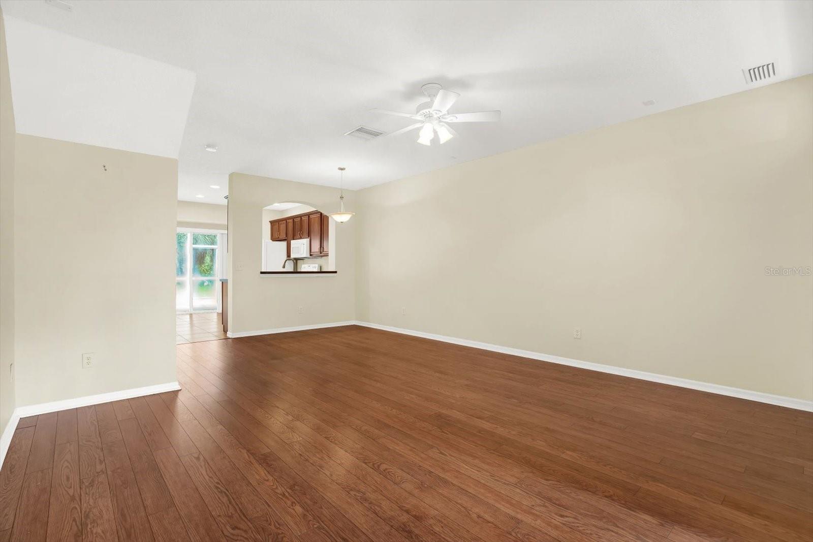 This spacious living room and dining room combo offers an open-concept design, seamlessly connecting to the kitchen for easy entertaining and flow. The rich wood flooring adds warmth and sophistication, while the layout maximizes space and functionality. A clever under-stair storage area is easily accessible, providing extra storage without sacrificing style.