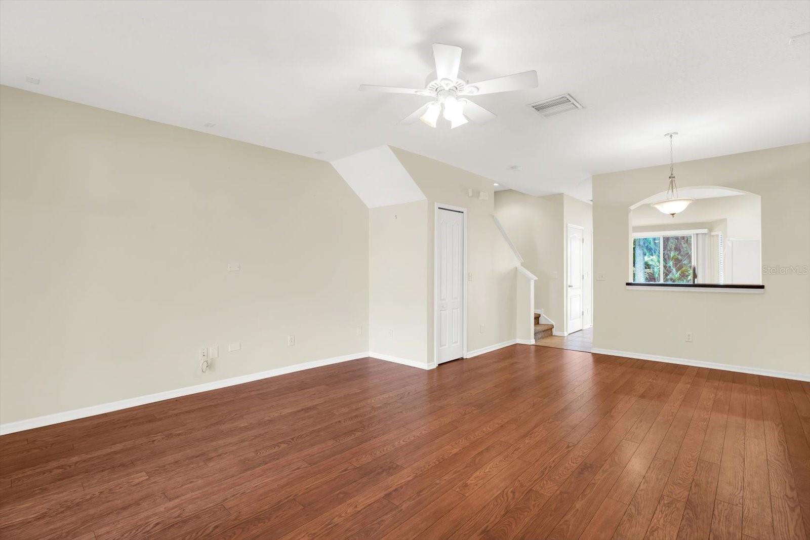 This spacious living room and dining room combo offers an open-concept design, seamlessly connecting to the kitchen for easy entertaining and flow. The rich wood flooring adds warmth and sophistication, while the layout maximizes space and functionality. A clever under-stair storage area is easily accessible, providing extra storage without sacrificing style.