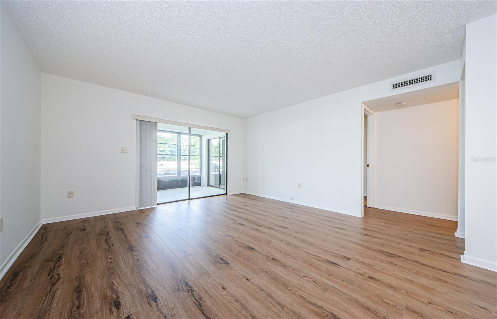 Living room with new luxury vinyl floors. Sliders to Screened and covered Lanai