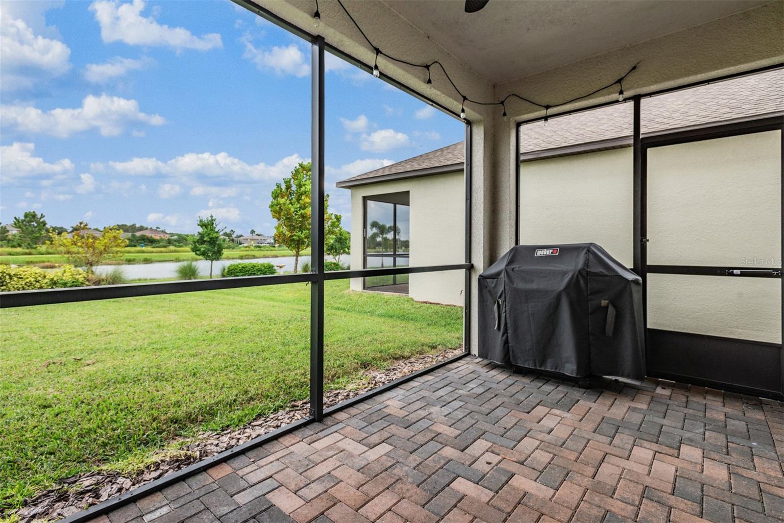 Covered screened patio overlooking large backyard with water views