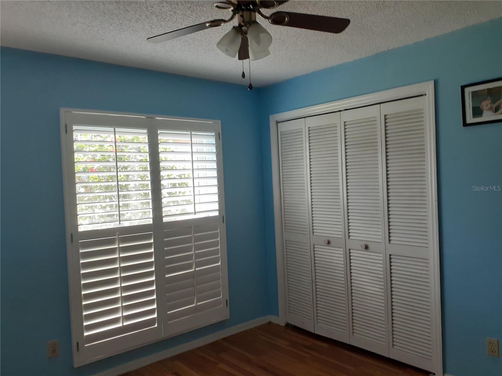 3rd bedroom with ceiling fan and double door closet