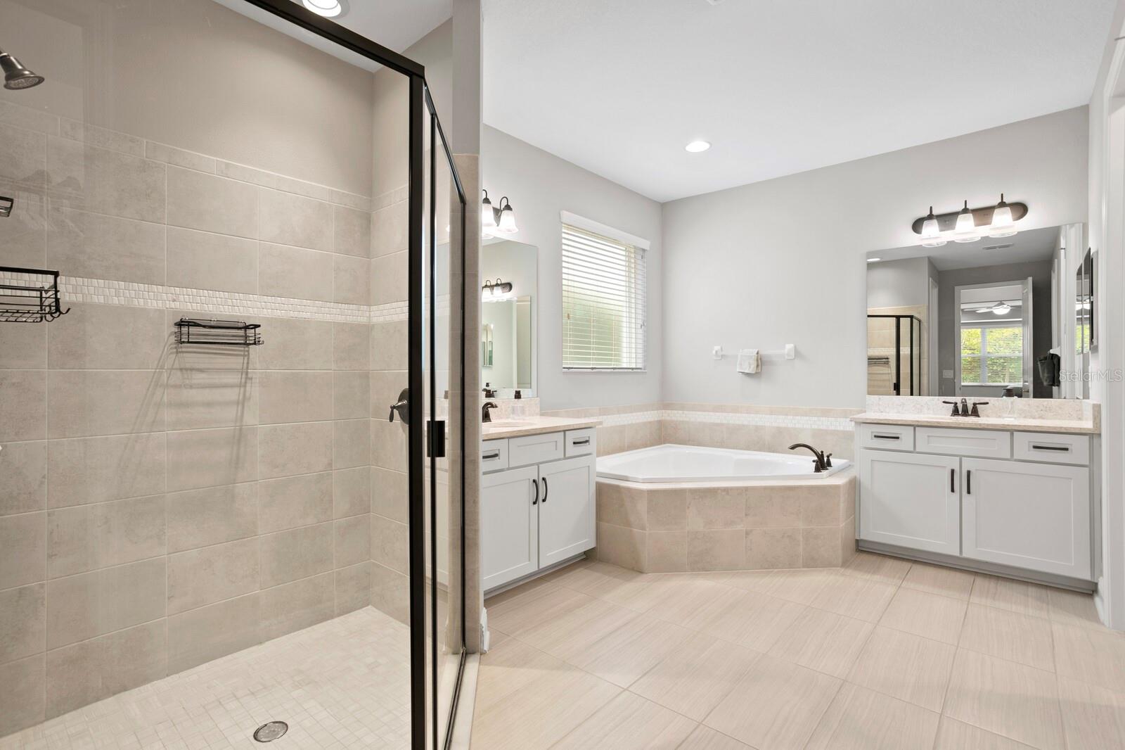 Ensuite bath to the primary has a walk in shower, tub, and two vanities.