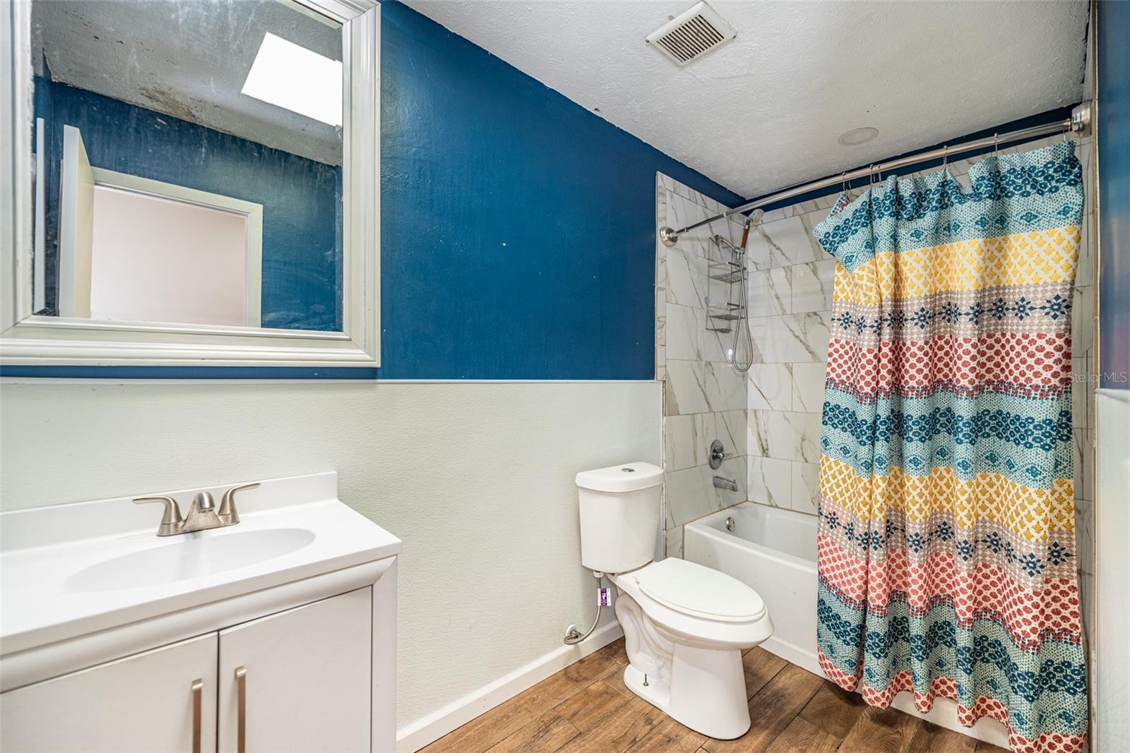 Guest bathroom shared by secondary bedrooms has a tub/shower combination and a bright skylight above.