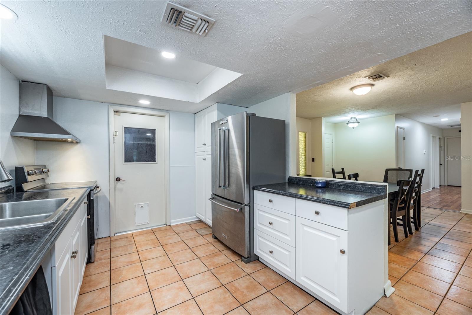 Garage door access and pantry storage next to refrigerator.