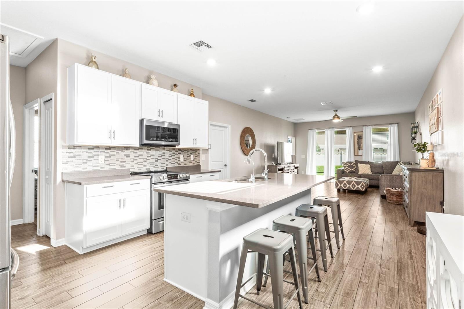 Tall cabinetry & quartz countertops adorn the kitchen.  Stainless steel appliances & island seating for 4.