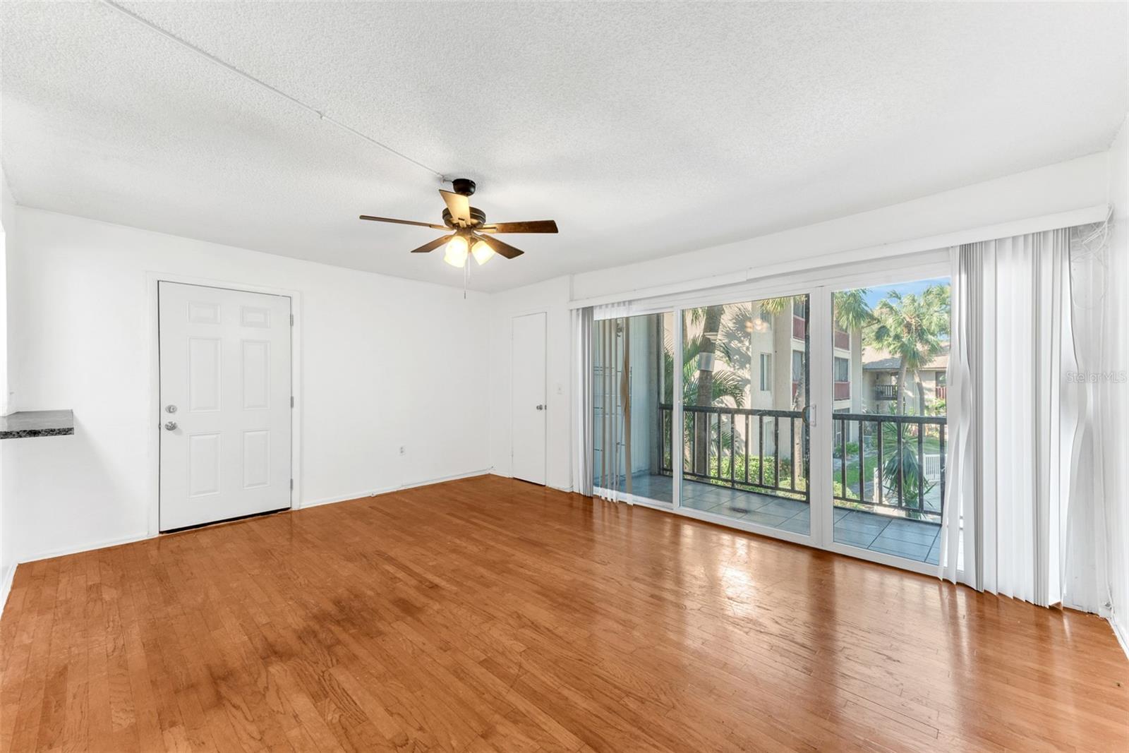 The high ceilings adorned with ceiling fans create an airy ambiance in this light filled living room. Convenient walk-in storage area next to sliders in the living room.