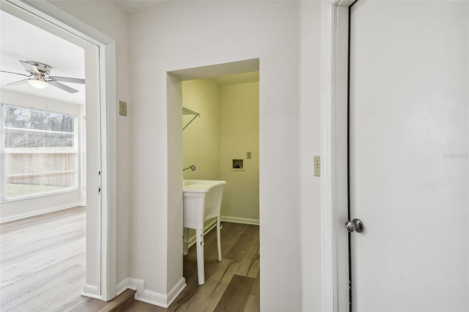 View from Hallway to doorway to Den/possible 3rd bedroom on left, laundry room in middle and doorway to garage on right.