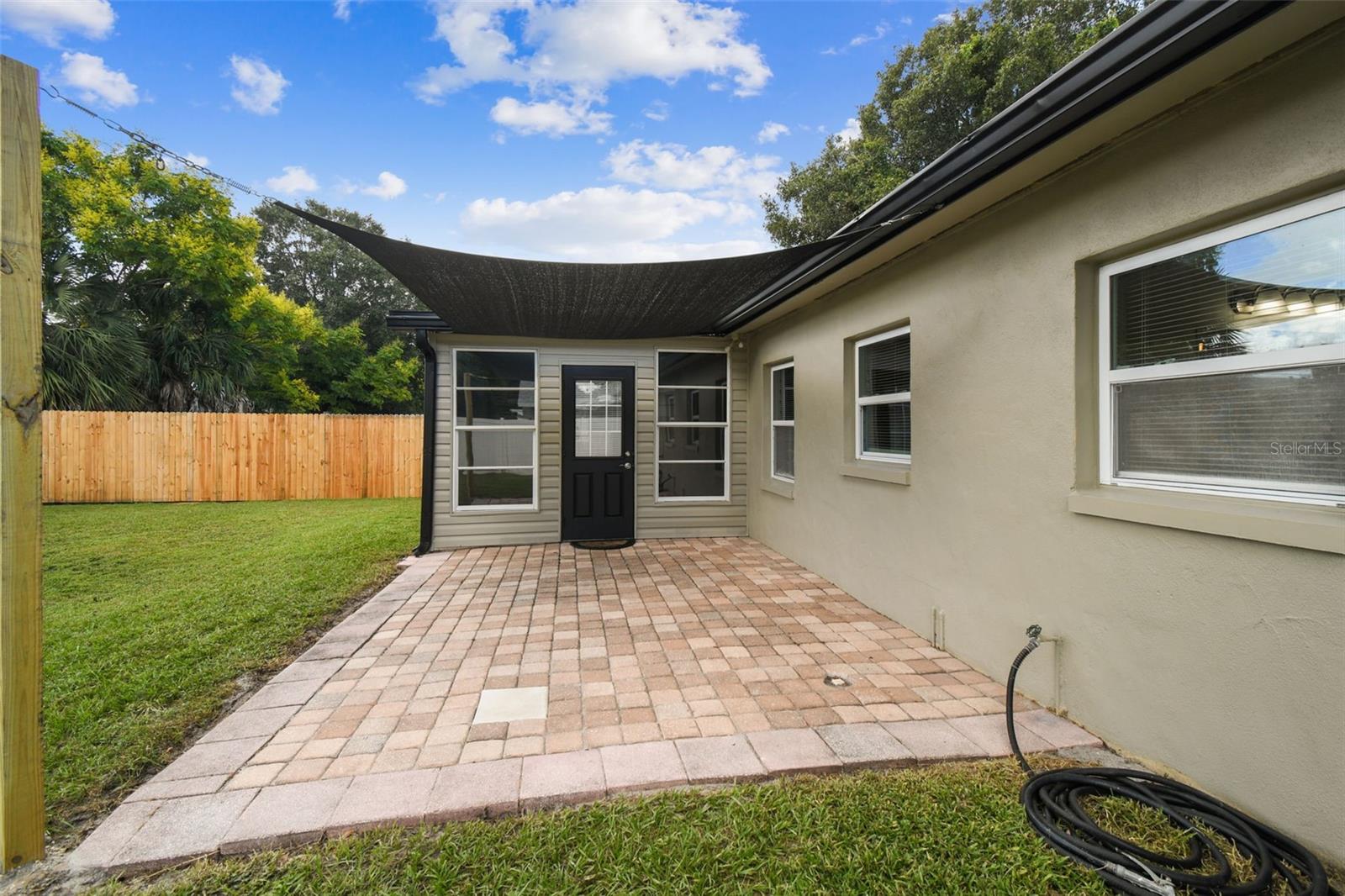 Large brick paved patio has a sun sail awning for shade!