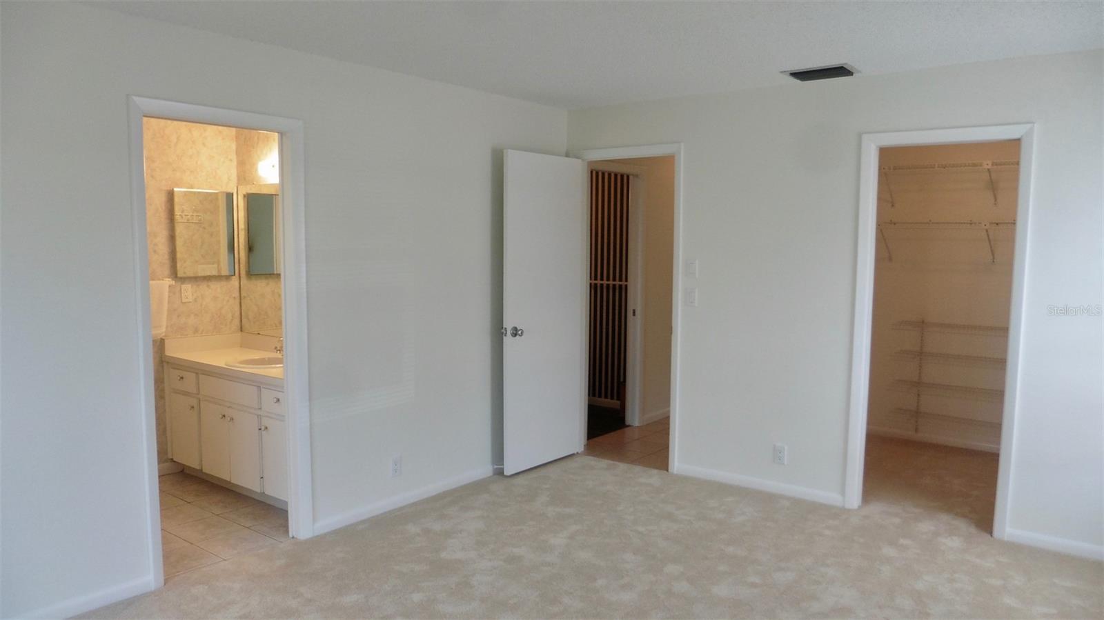 View from the Primary bedroom showing the large walk in closet, entry from the hall, and entrance to the rest room.