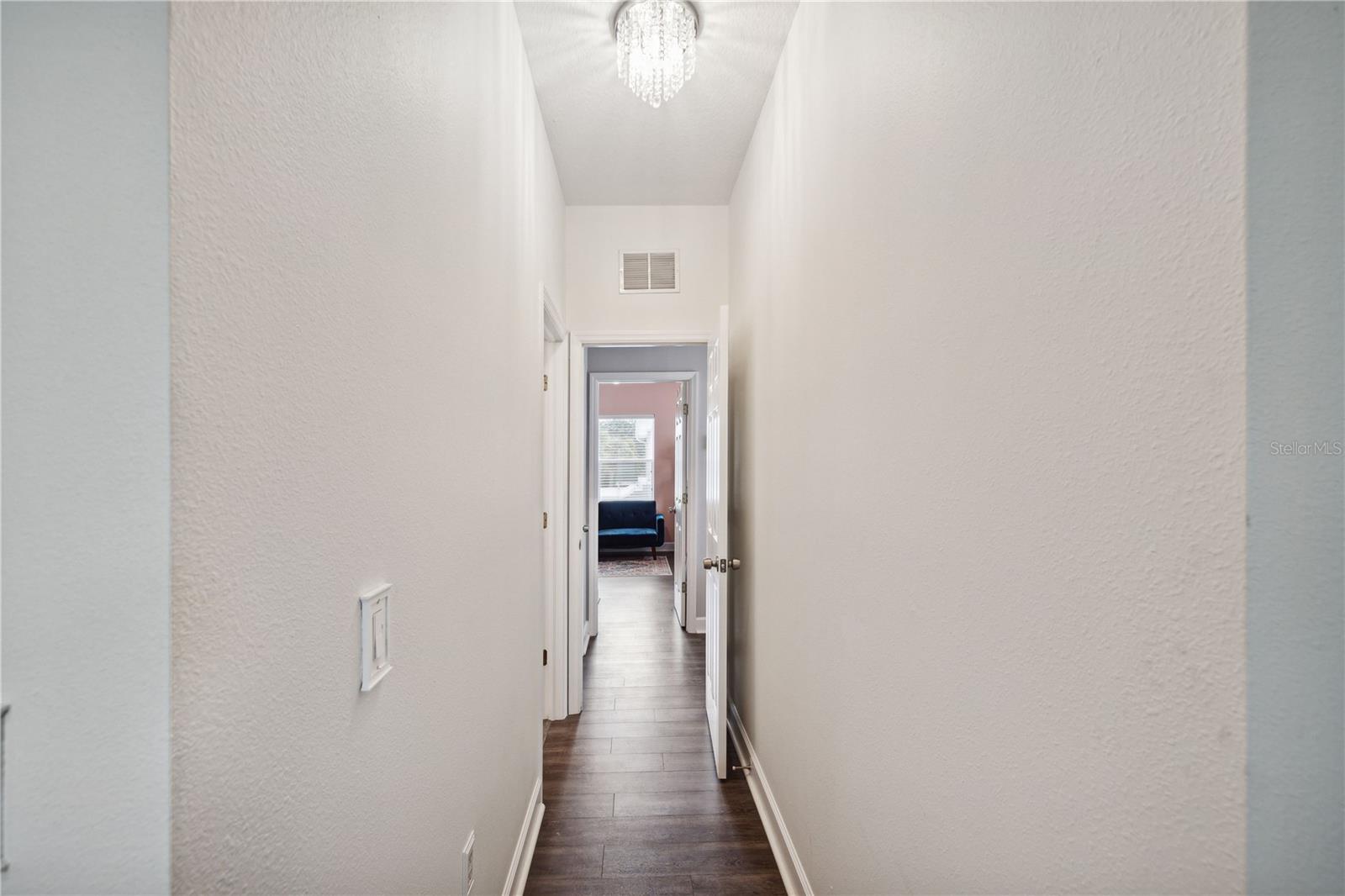 hallway into primary bedroom with designer light fixtures