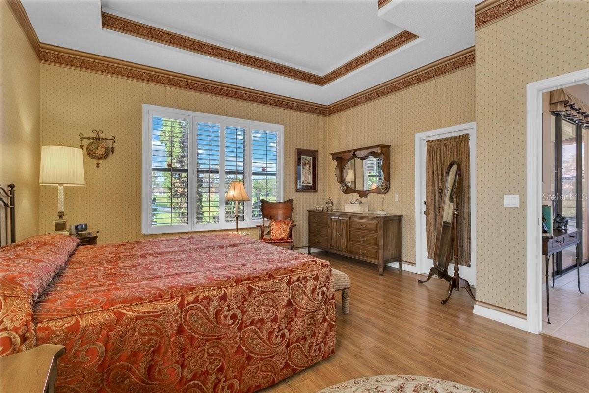 Primary bedroom with plantation shutters, tray ceiling and french door to lanai