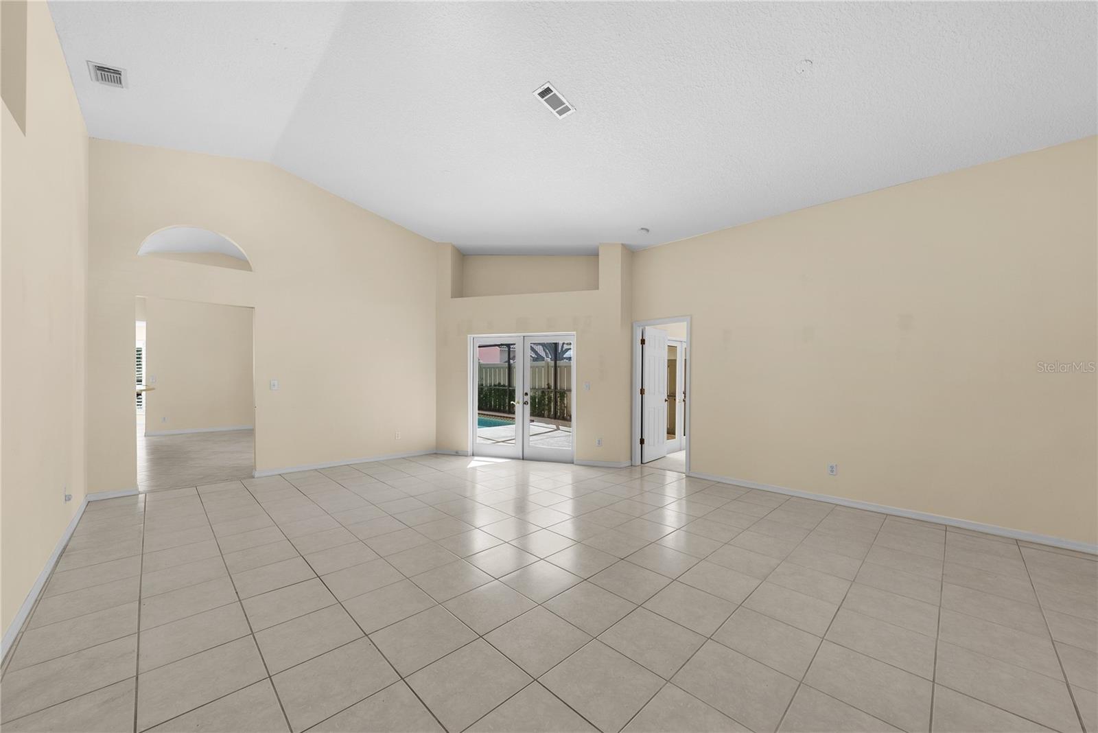 Living room leading to the kitchen and French doors out to the pool.