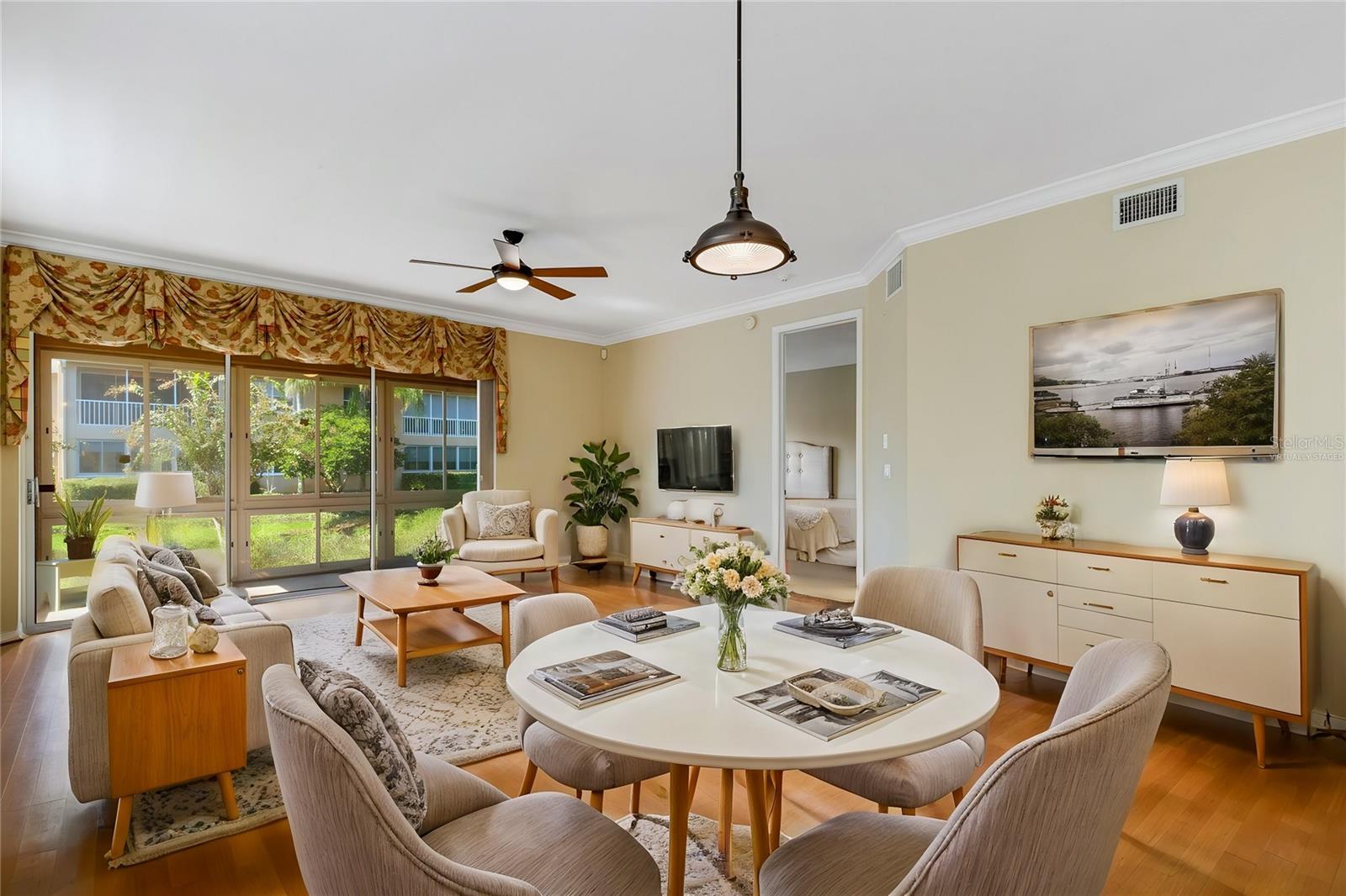 Dining room/living room with slider to lanai, primary bedroom to the right; virtually staged