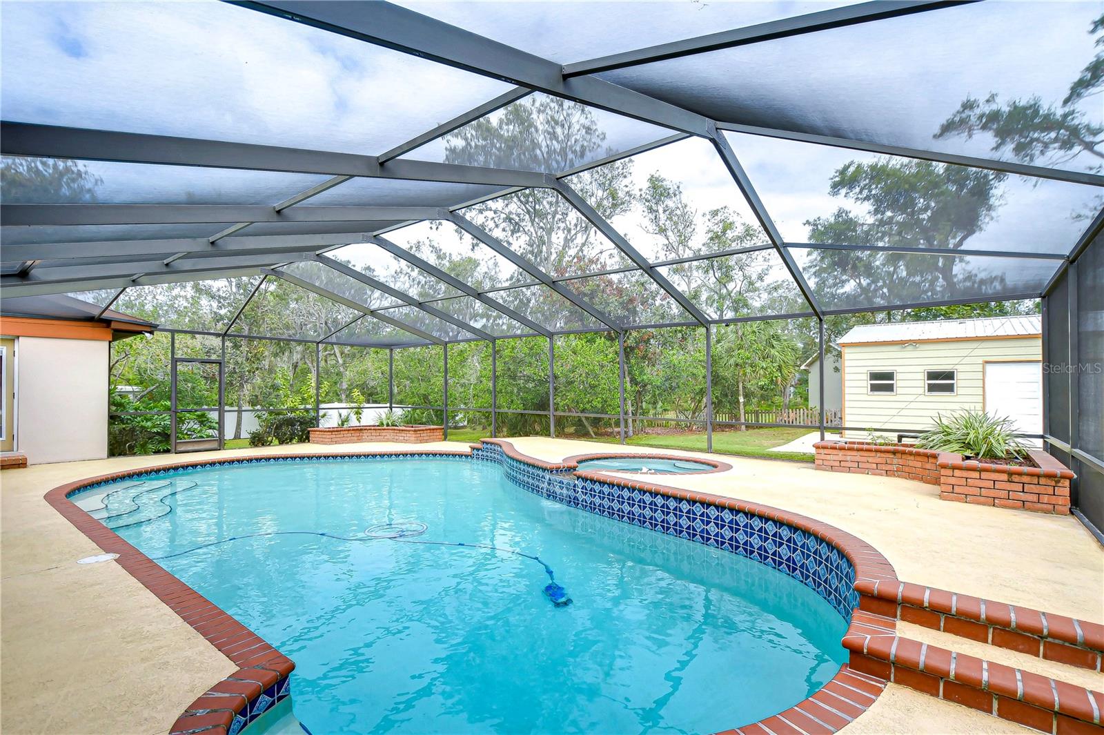 Covered and screened lanai with a sparkling pool and lush garden views!