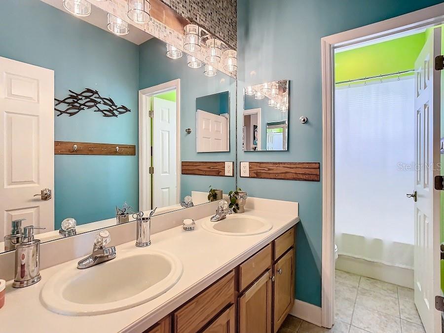 Upstairs full bath with two sinks and closed off space for commode and tub with shower