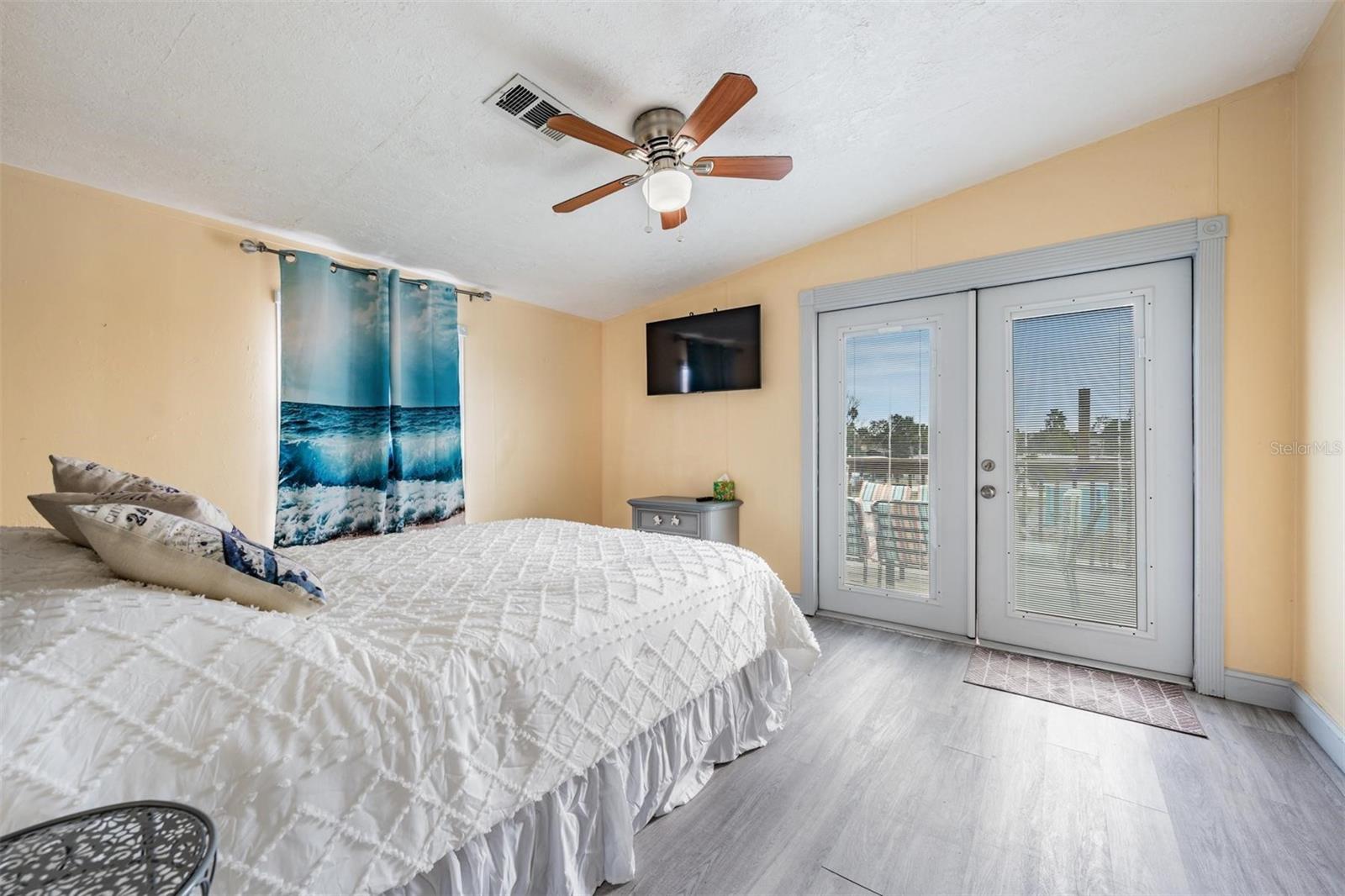 Primary bedroom has French doors leading to the wrap around deck that overlooks the canal