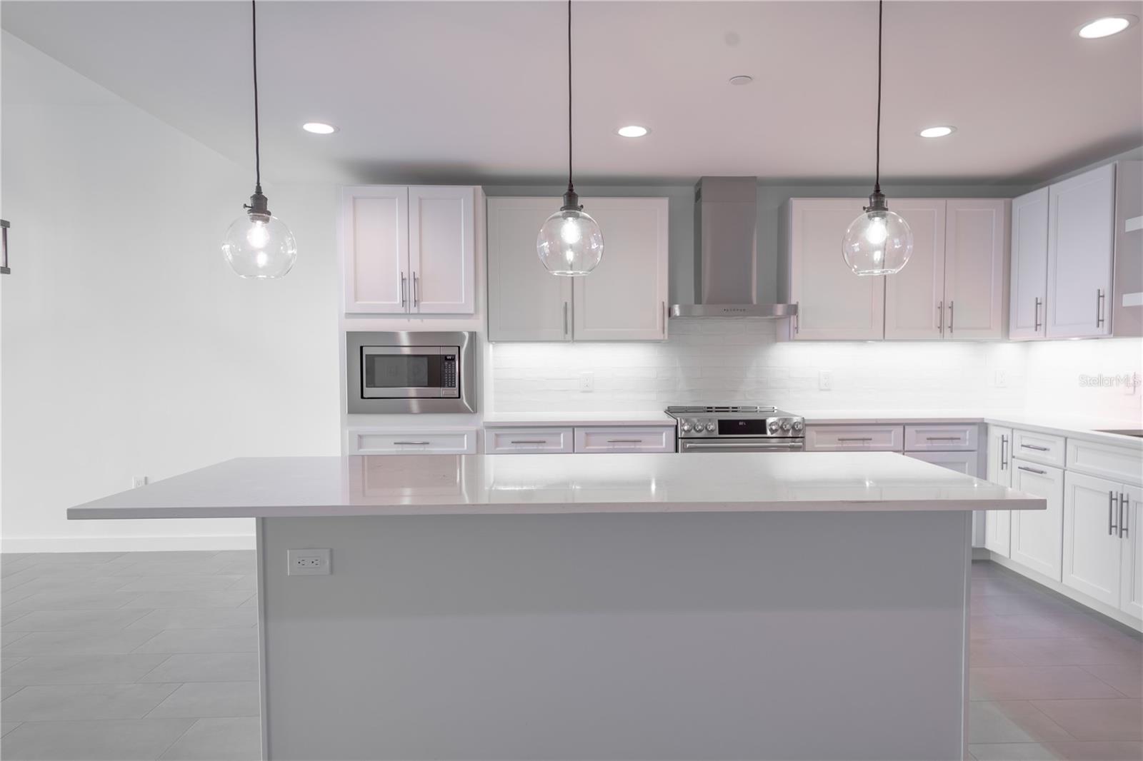 Three hand-blown, glass-inspired, head-turning pendant lights illuminate the kitchen island beautifully.