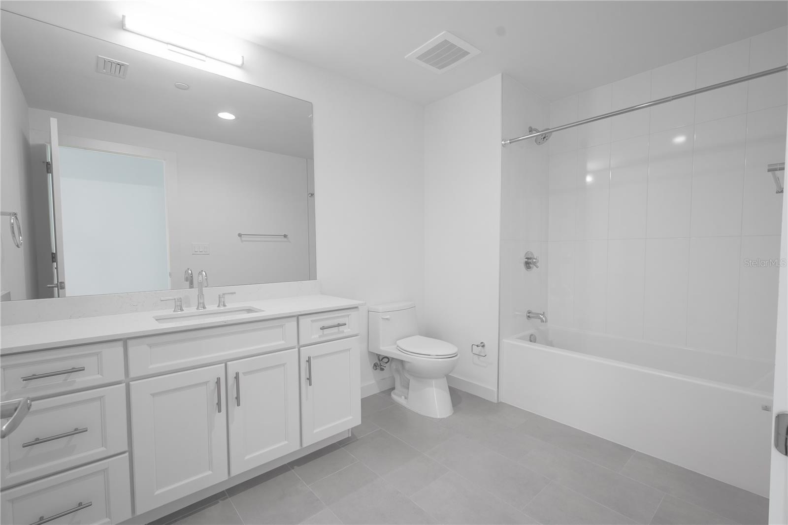 Bathroom 2 is spacious and features a soaking tub with shower, porcelain tile flooring, a mirrored vanity with storage.