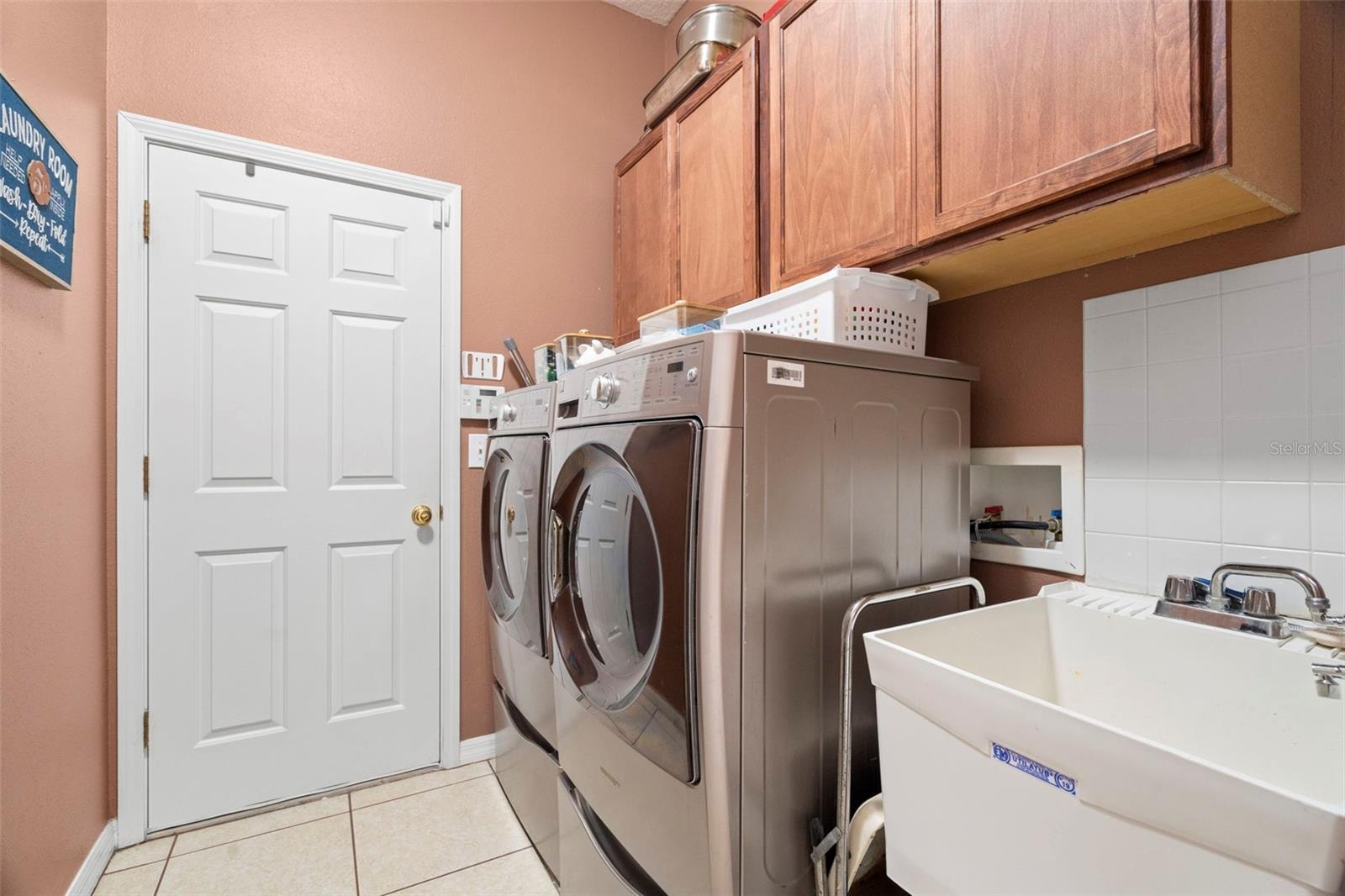 Inside laundry room with auxiliary sink and upscale appliances