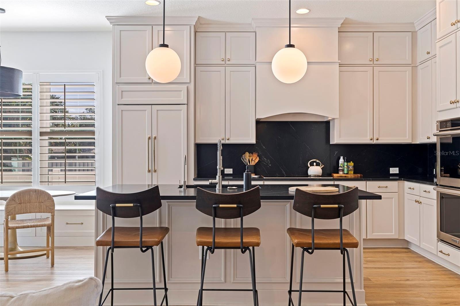 Stunning custom hood above the induction cooktop. Paneled Subzero refrigerator, island seating as well as sink & paneled COVE dishwasher.