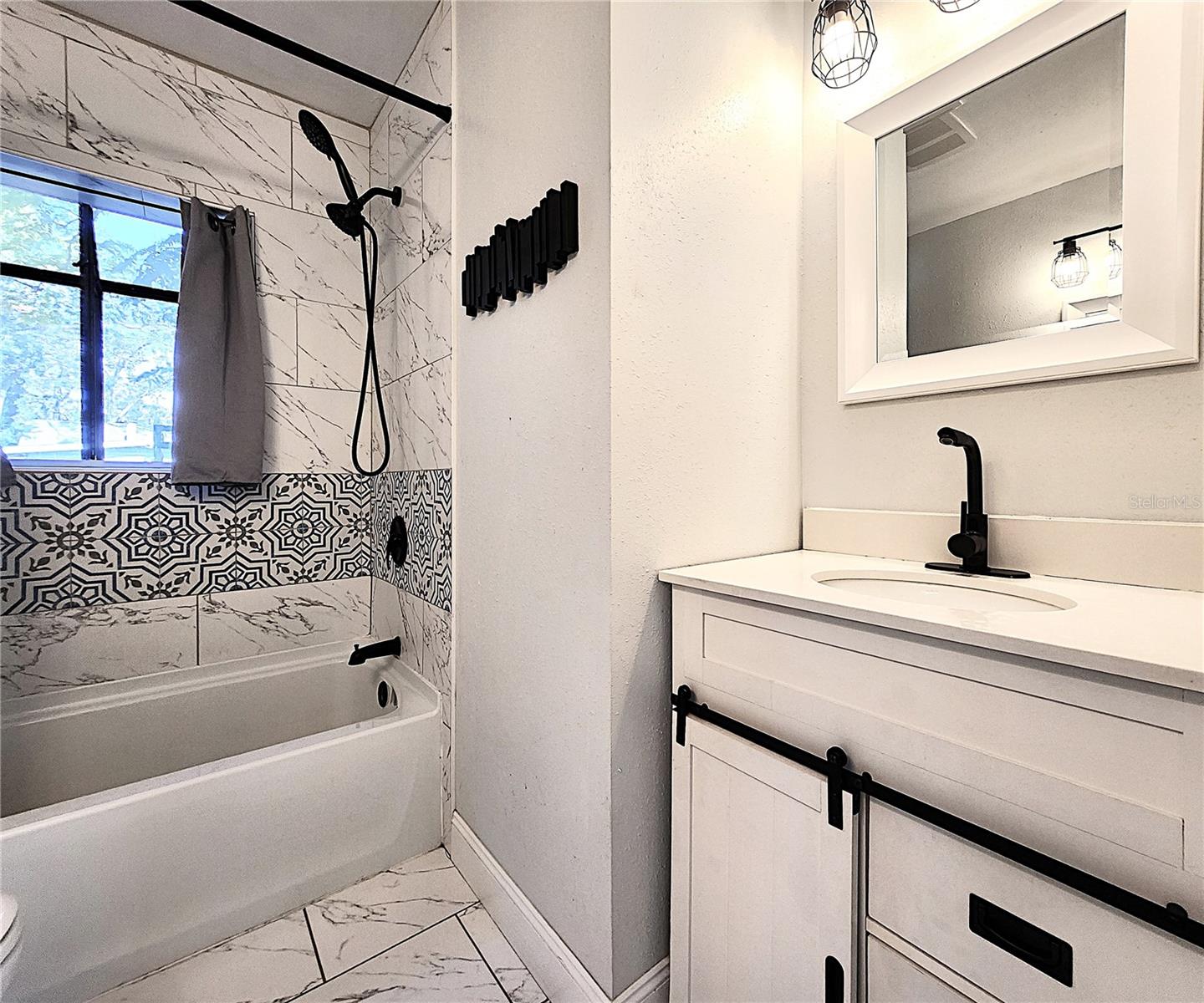 Bathroom includes split vanities, tiled shower/tub combo