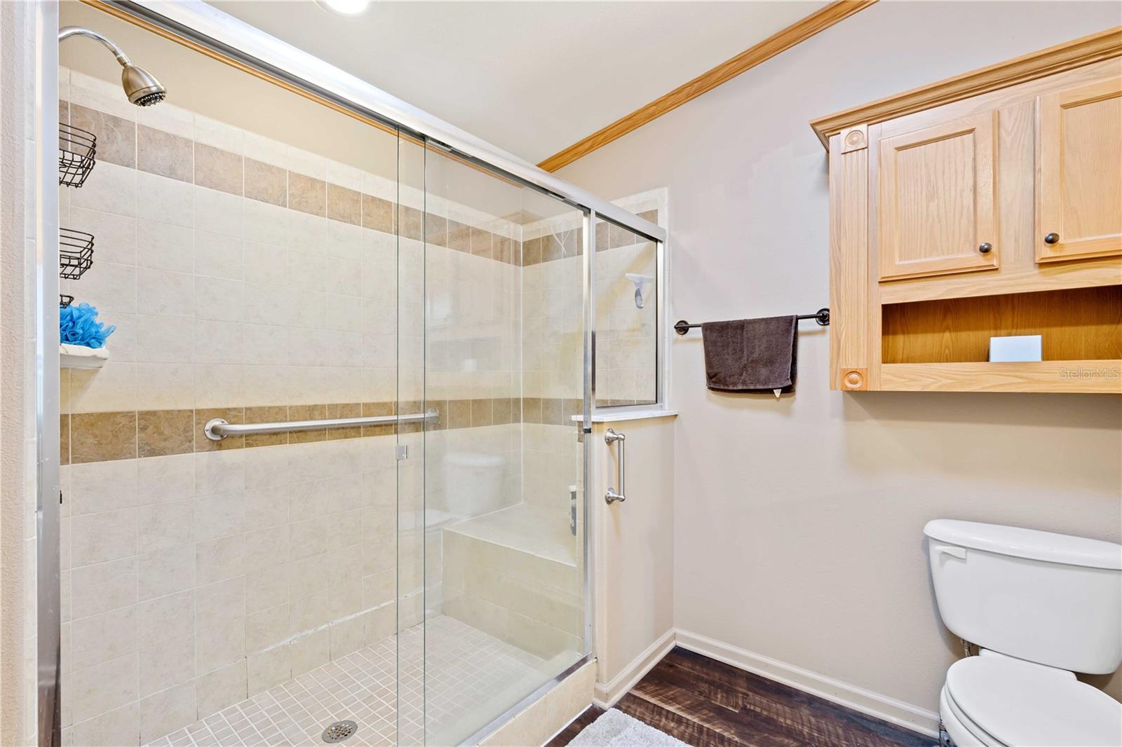 Shower is tiled with glass doors.