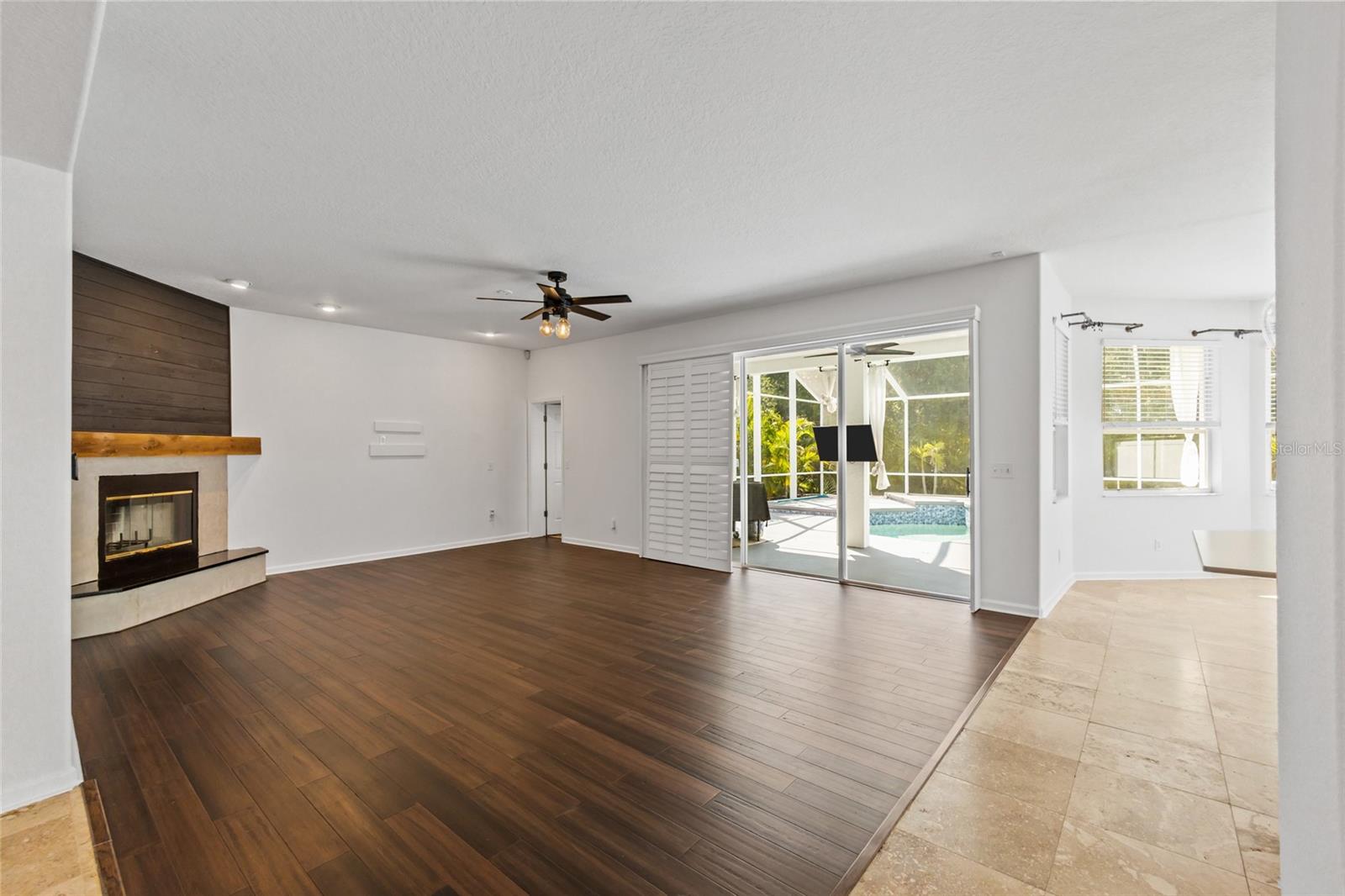 FAMILY ROOM WITH VIEW TO LANAI & POOL AREA. SLIDING CUSTOM PLANTATION SHUTTERS