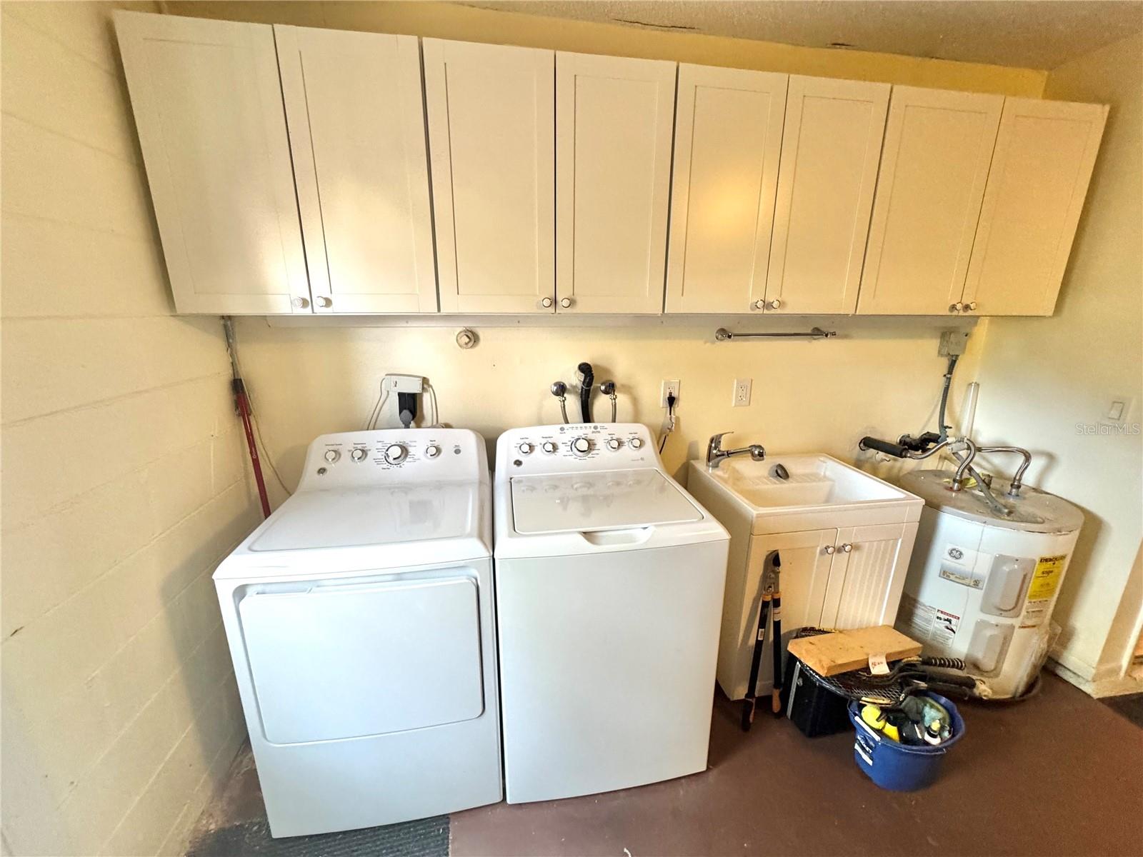 Upper cabinets and an auxiliary sink accompany the washer & dryer in the garage.