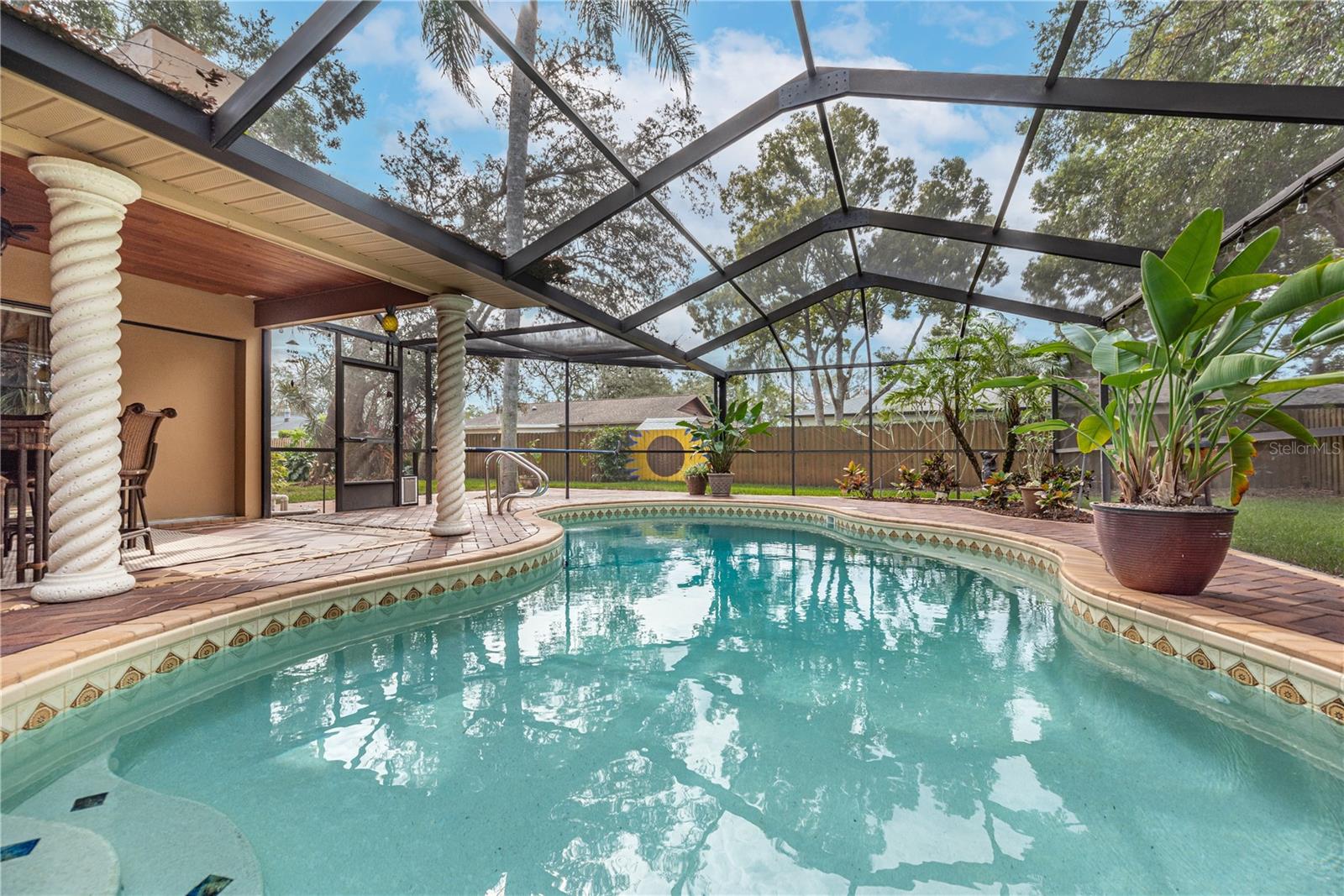 The pool is heated and the screened lanai leads to an open pavered patio and fenced large yard.