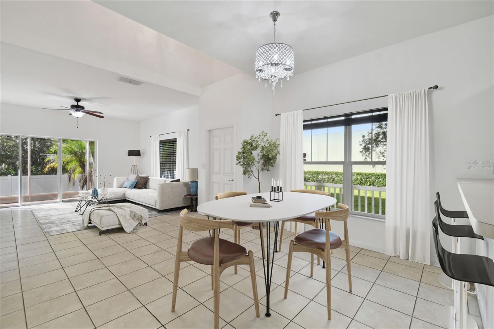 open concept style living room with view of the backyard's tree line (virtually staged)