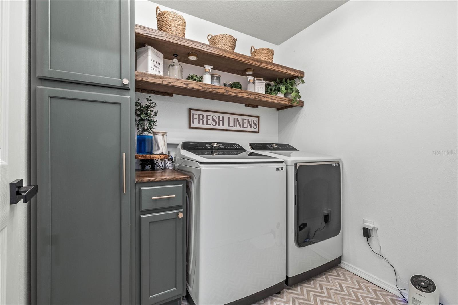 The laundry room has added cabinetry, shelving, and a herringbone laid tile floor.