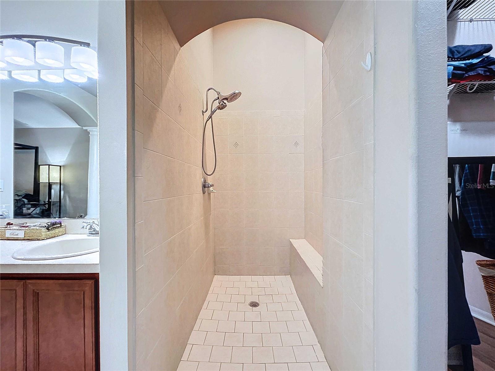 Large primary bathroom walk-in shower with bench