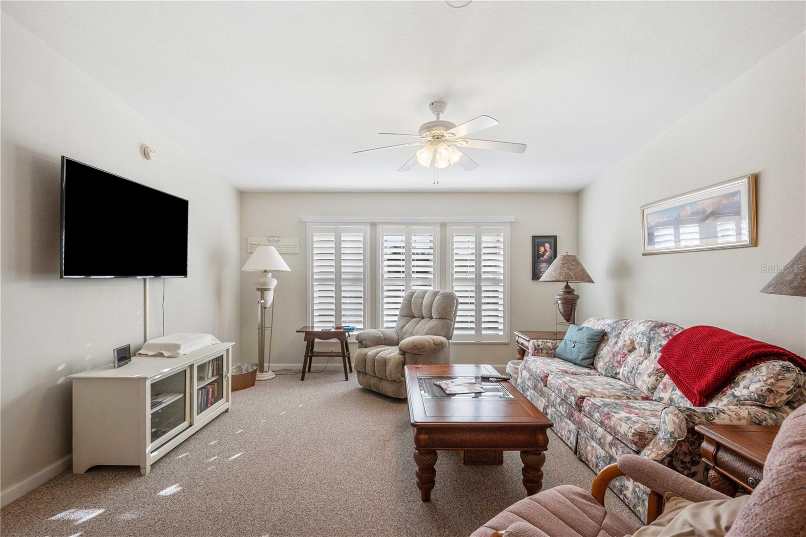 Plantation shutter, ceiling fan are part of this living room area.