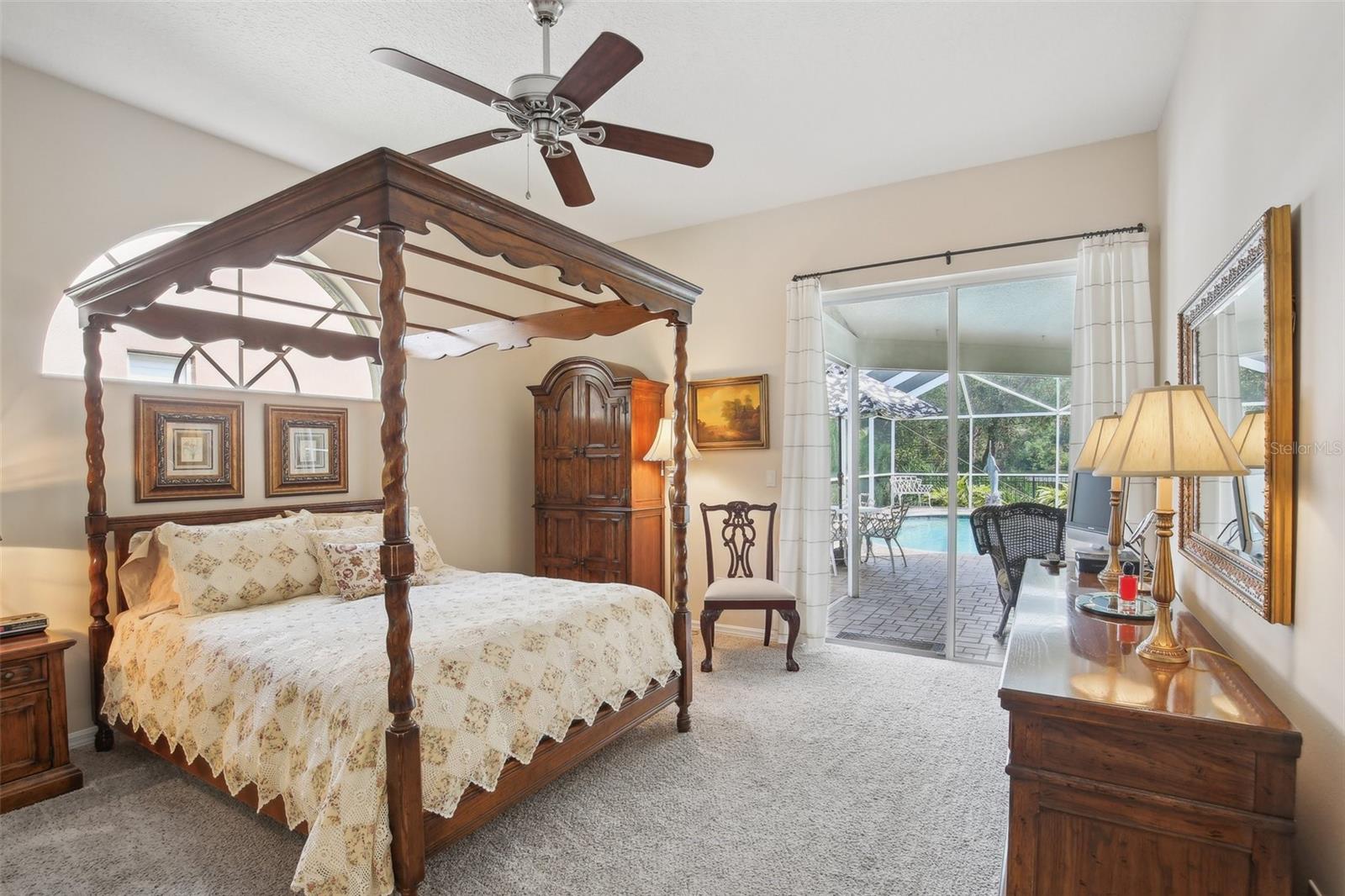 Primary bedroom with water view and glass sliding door to pool area