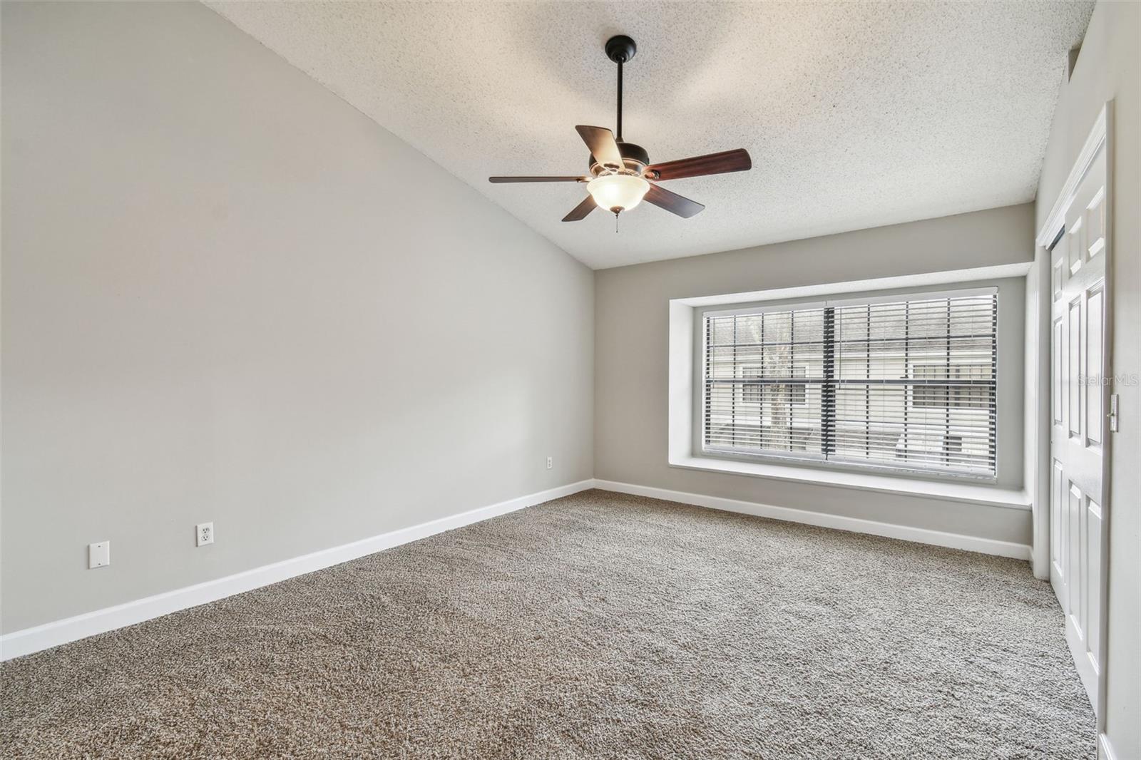 Primary bedroom is oversized with vaulted ceilings, large windows with a window seat and a custom closet.