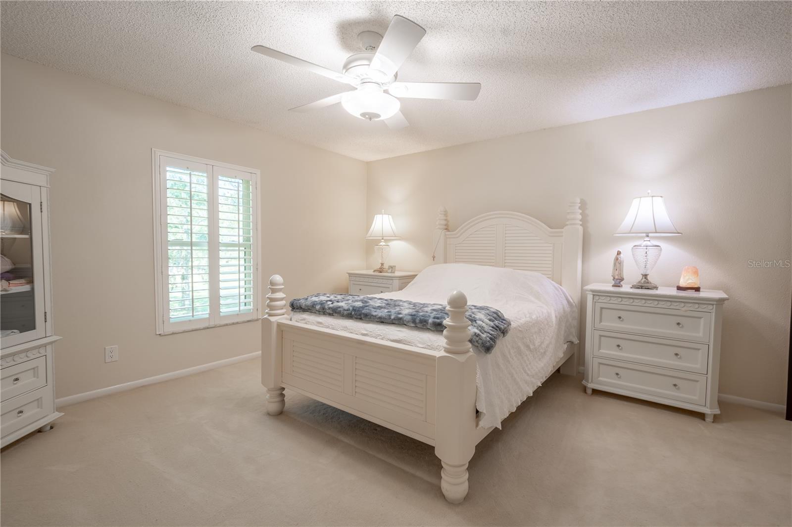 The primary bedroom is poised for a good nights rest with plush carpeting, a calming color palette and a ceiling fan with light kit.