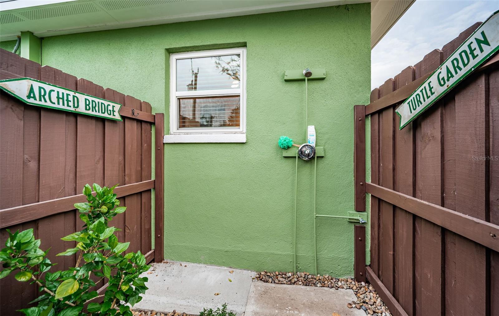 The outdoor shower space is adorned with vintage signs from Sunken Gardens.