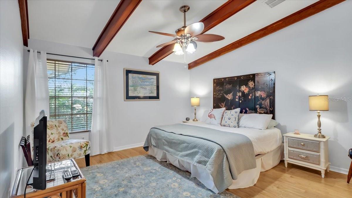 Master bedroom with vaulted ceiling, oak beams and ceiling fan.