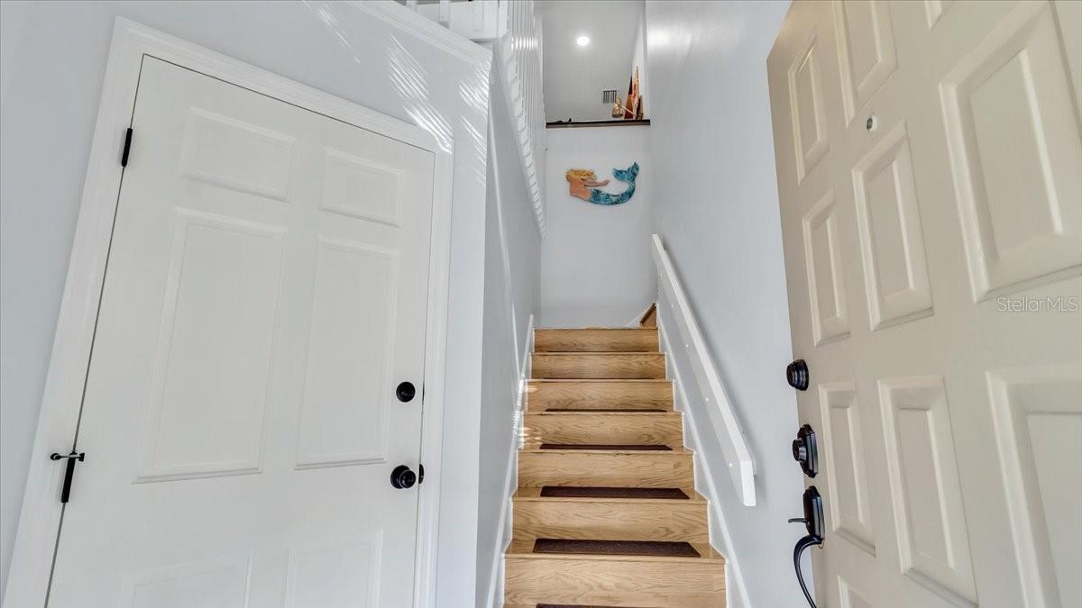 Large foyer with new custom porcelain tile and oak hardwood stairs. Garage entrance to the left.