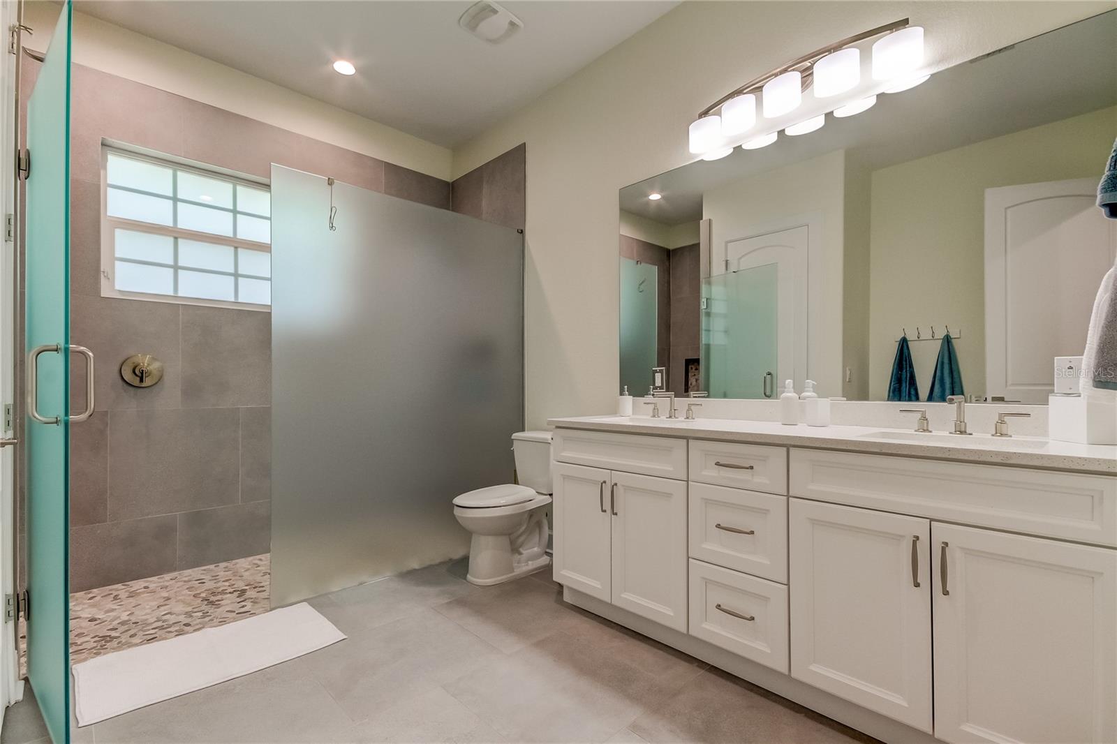 3rd full bath on main floor, oversized with dual sinks and zero-entry shower.