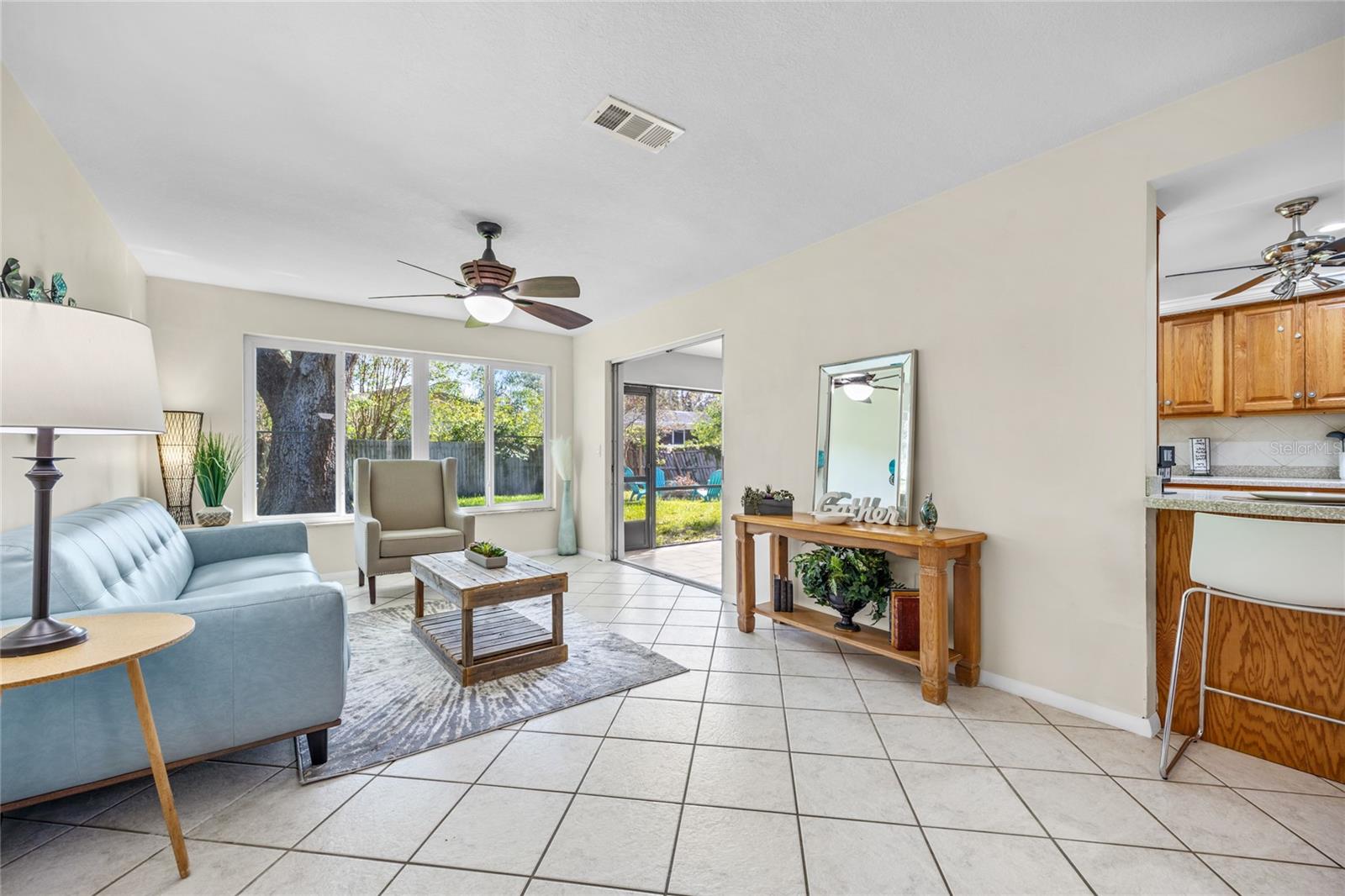 The casual Family Room features large windows that frame a beautiful view of the backyard, while offering direct access to the screened lanai, creating a seamless indoor-outdoor living experience.