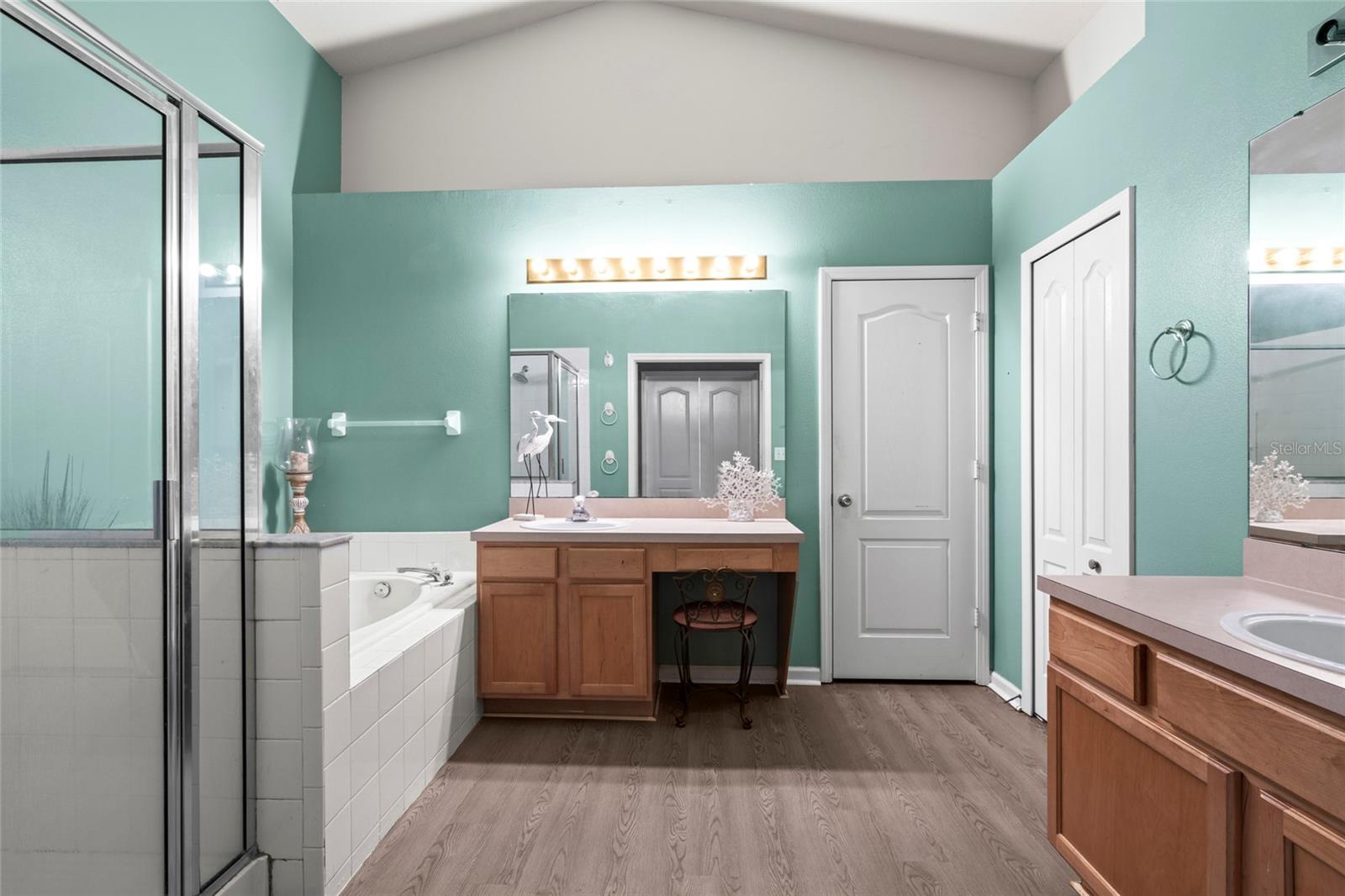 Master Bathroom with vaulted ceilings, dual sinks, garden tub, shower, water closet, and linen closet