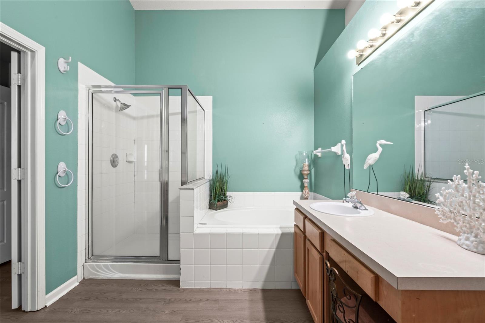 Master Bathroom with vaulted ceilings, dual sinks, garden tub, shower, water closet, and linen closet