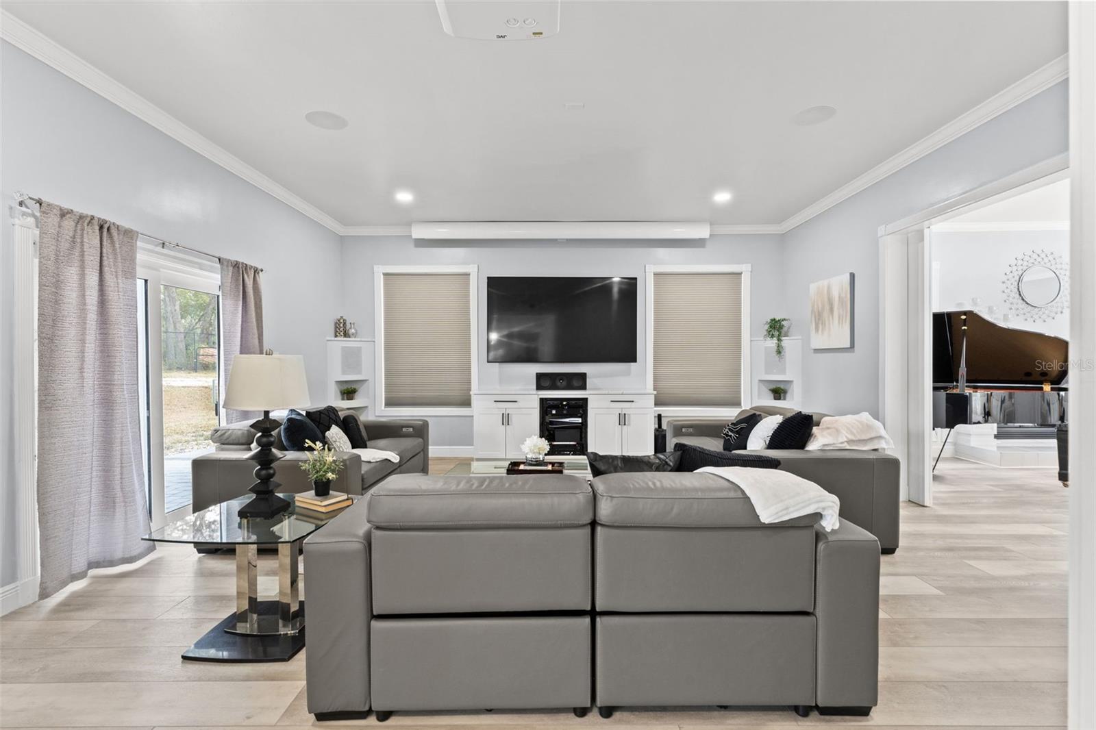 Living Room with built in speaker and sliding doors that lead to the pool and backyard oasis