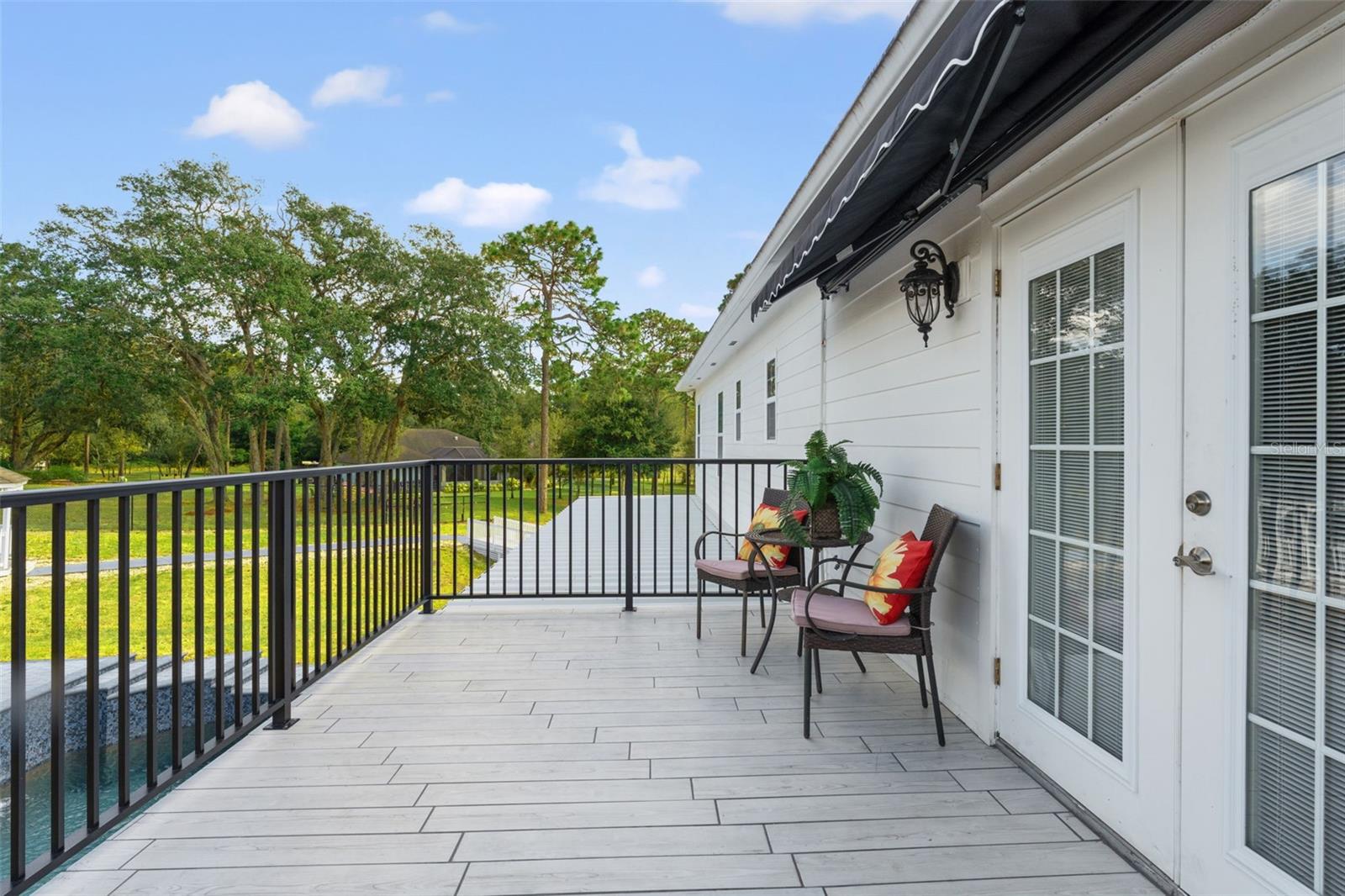 A private balcony fron the masters suite featuring new tile, railing, and an awning, offering serene views of the pool for ultimate relaxation.