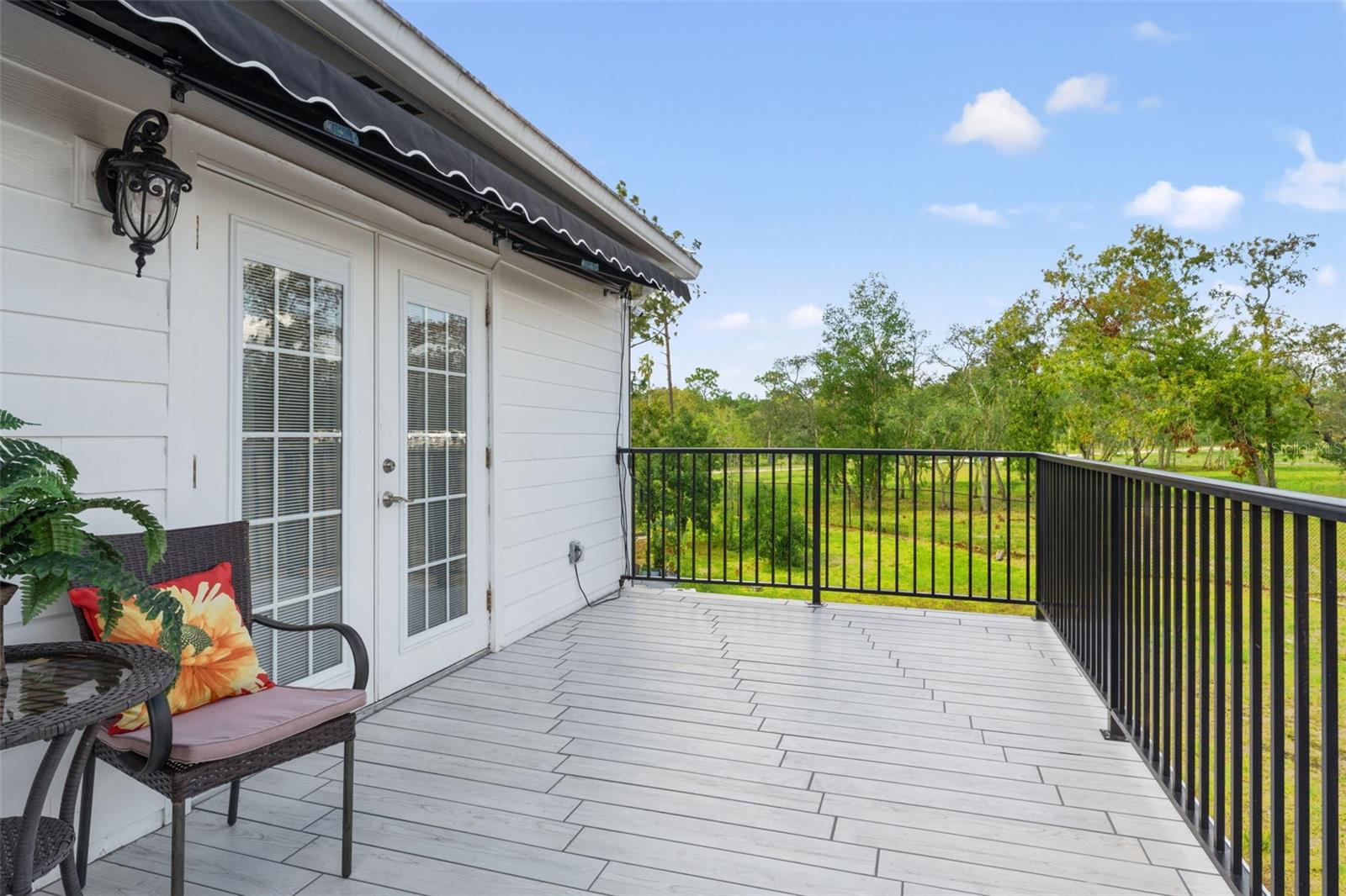 A private balcony fron the masters suite featuring new tile, railing, and an awning, offering serene views of the pool for ultimate relaxation.