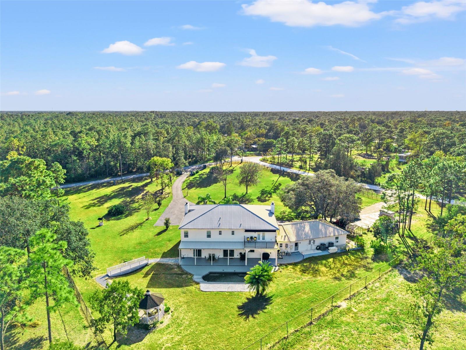 Aerial view of this Colonial-inspired estate, designed with the grandeur reminiscent of the iconic “White House.” Set on a private 2.40-acre property