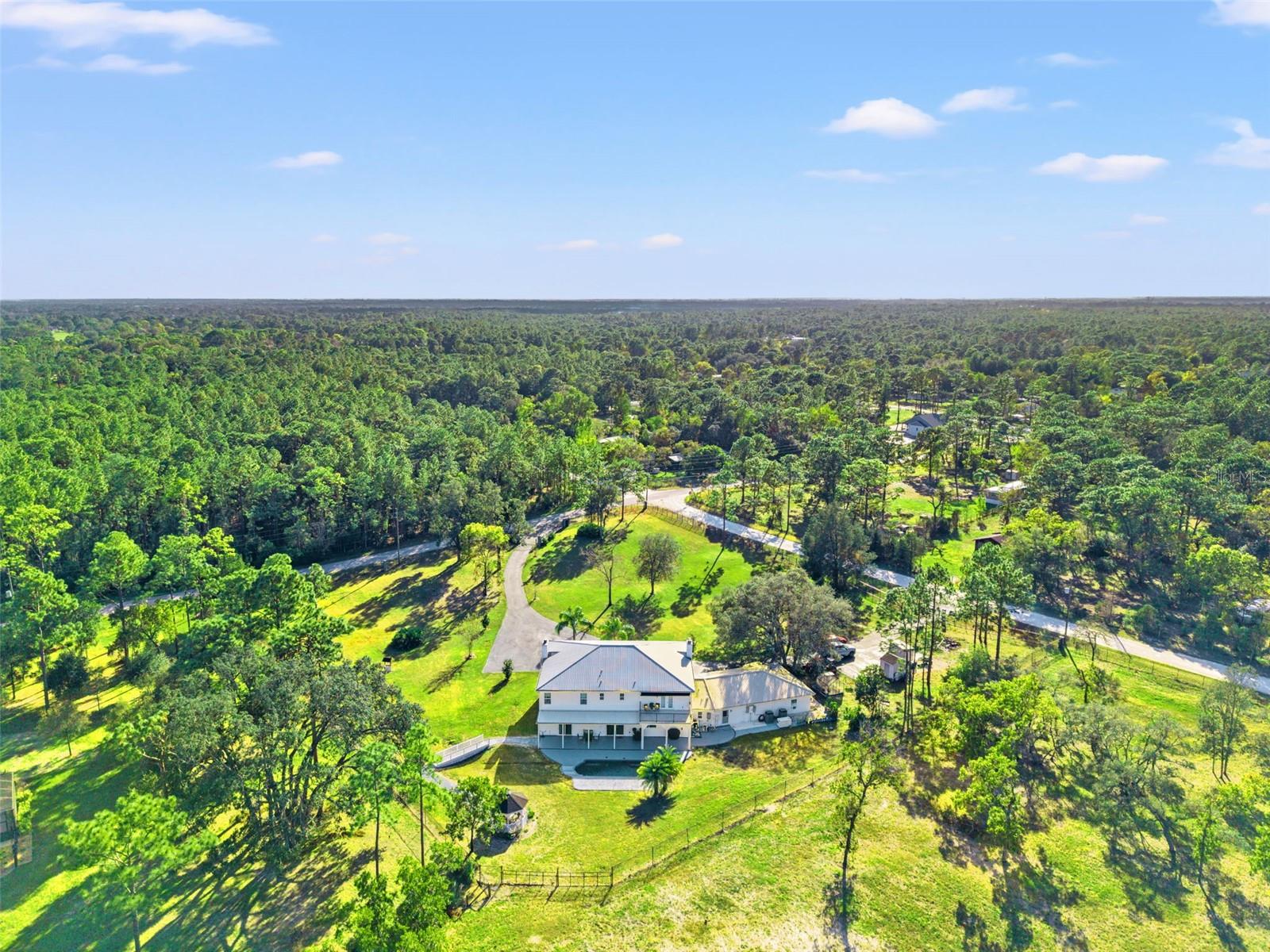 Aerial view of this Colonial-inspired estate, designed with the grandeur reminiscent of the iconic “White House.” Set on a private 2.40-acre property